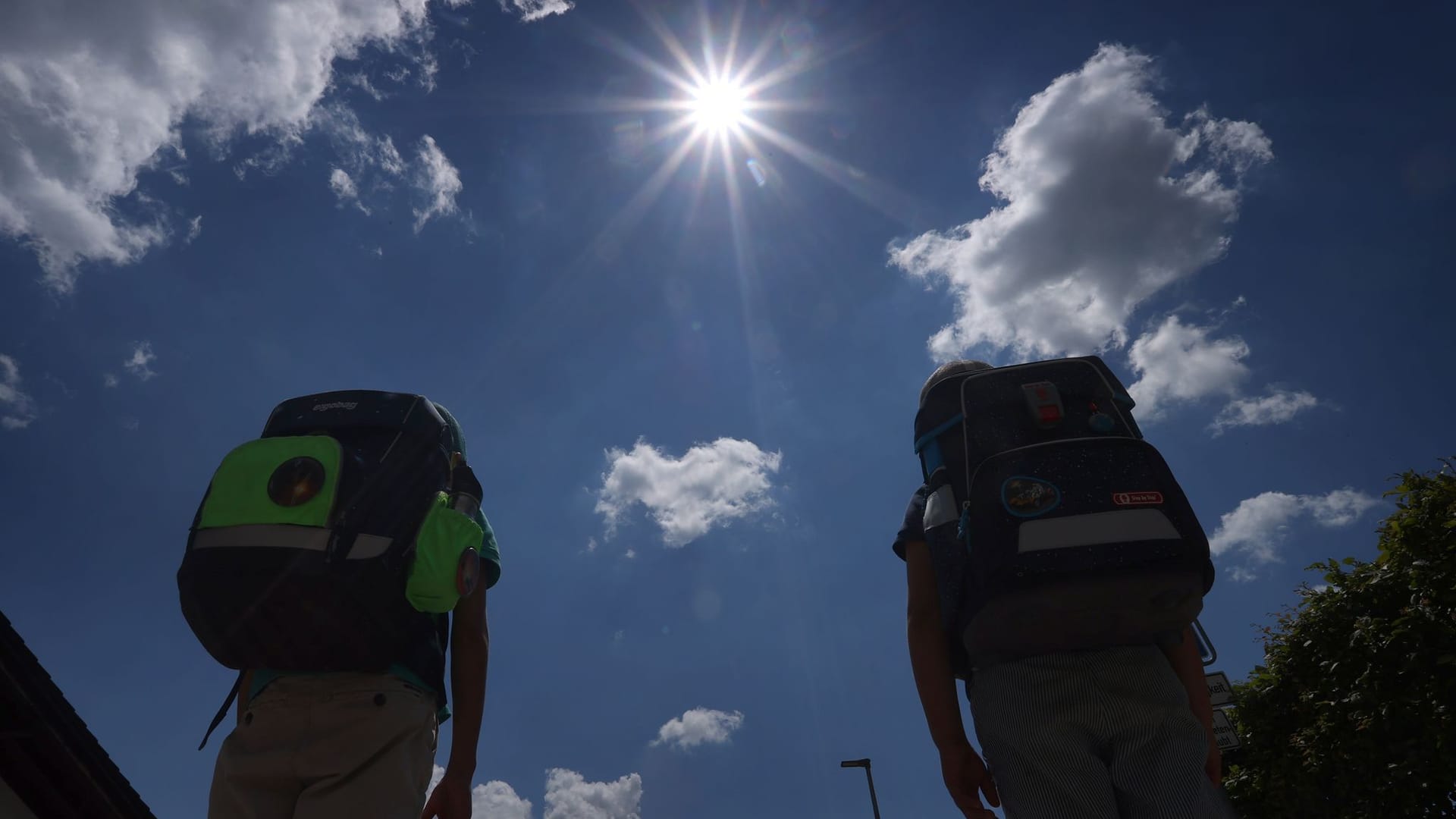 Zwei Schüler mit Ranzen laufen im Sonnenschein