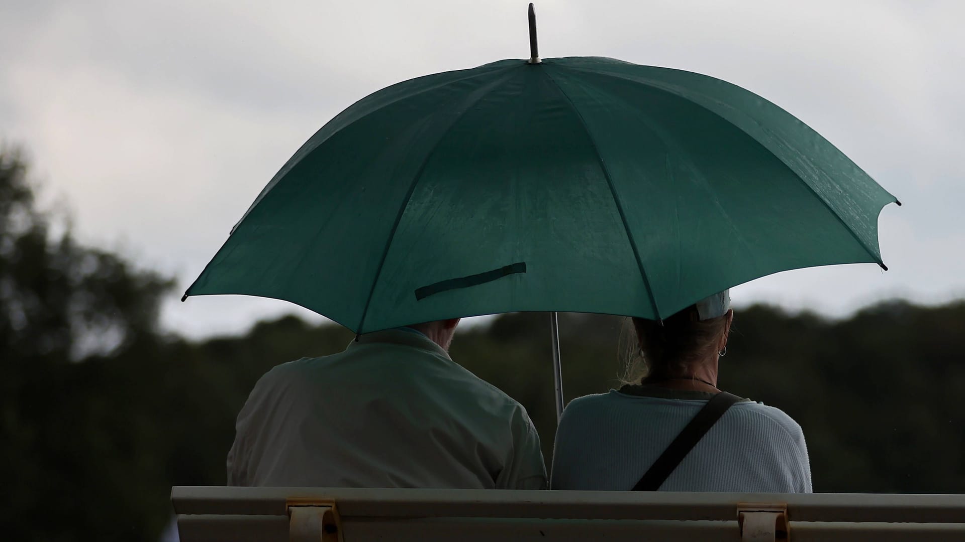 Ein Paar sitzt bei Regen mit Regenschirm auf einer Bank (Symbolbild): Sonne, Regen und Gewitter werden in Niedersachsen erwartet. Ein Paar sitzt bei Regen mit Regenschirm auf einer Bank (Symbolbild): Sonne, Regen und Gewitter werden in Niedersachsen erwartet.