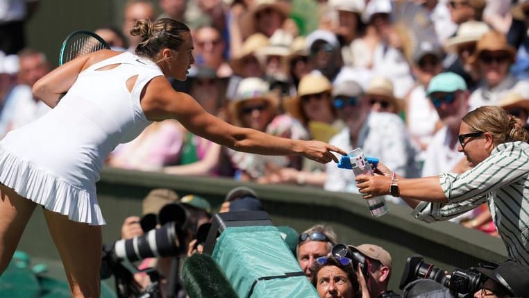 Hilfe vom Tennis-Superstar: Aryna Sabalenka reicht eine Wasserflasche ins Publikum.