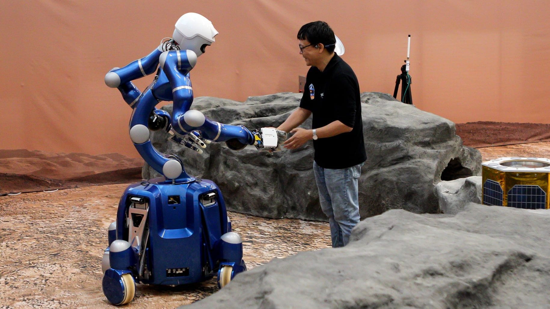 DLR-Forscher Dr. Neal Y. Lii reicht dem humanoiden Roboter "Rollin’ Justin" seine Hand: Der Roboter erwidert den Händedruck durch die Steuerung von NASA-Astronaut Jonny Kim.