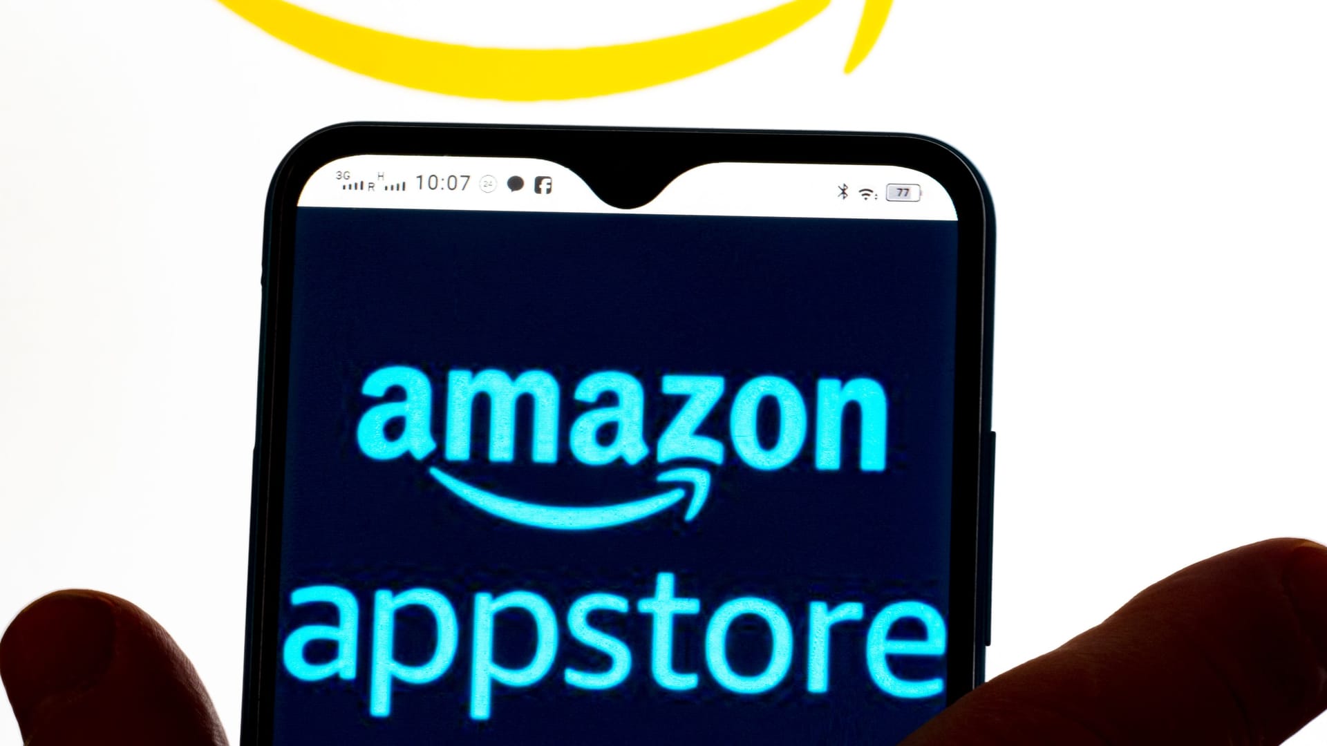In this photo illustration, the Amazon AppStore logo is seen displayed on a smartphone screen and Amazon logo in the background.