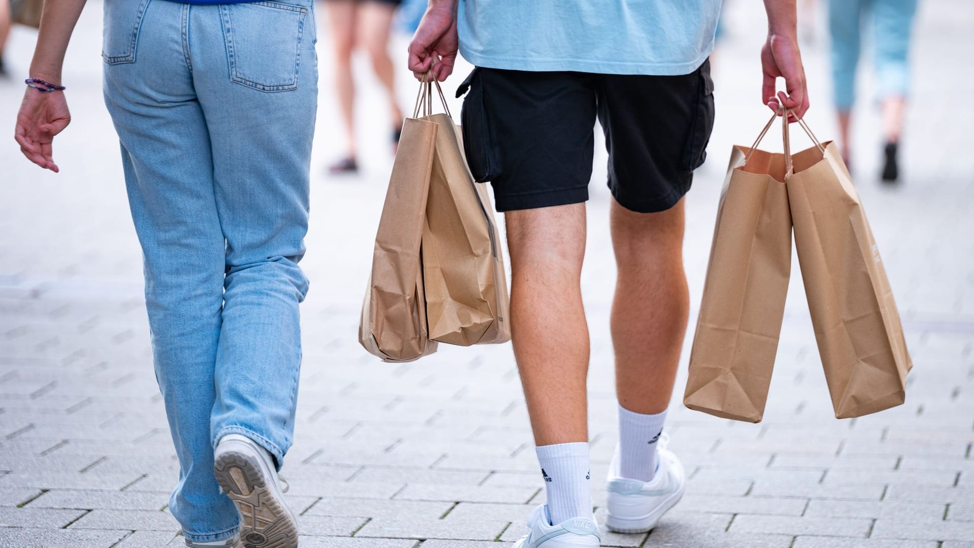 Menschen in einer Fußgängerzone mit Papiertüten beim Shopping Menschen in einer Fußgängerzone mit Papiertüten beim Shopping