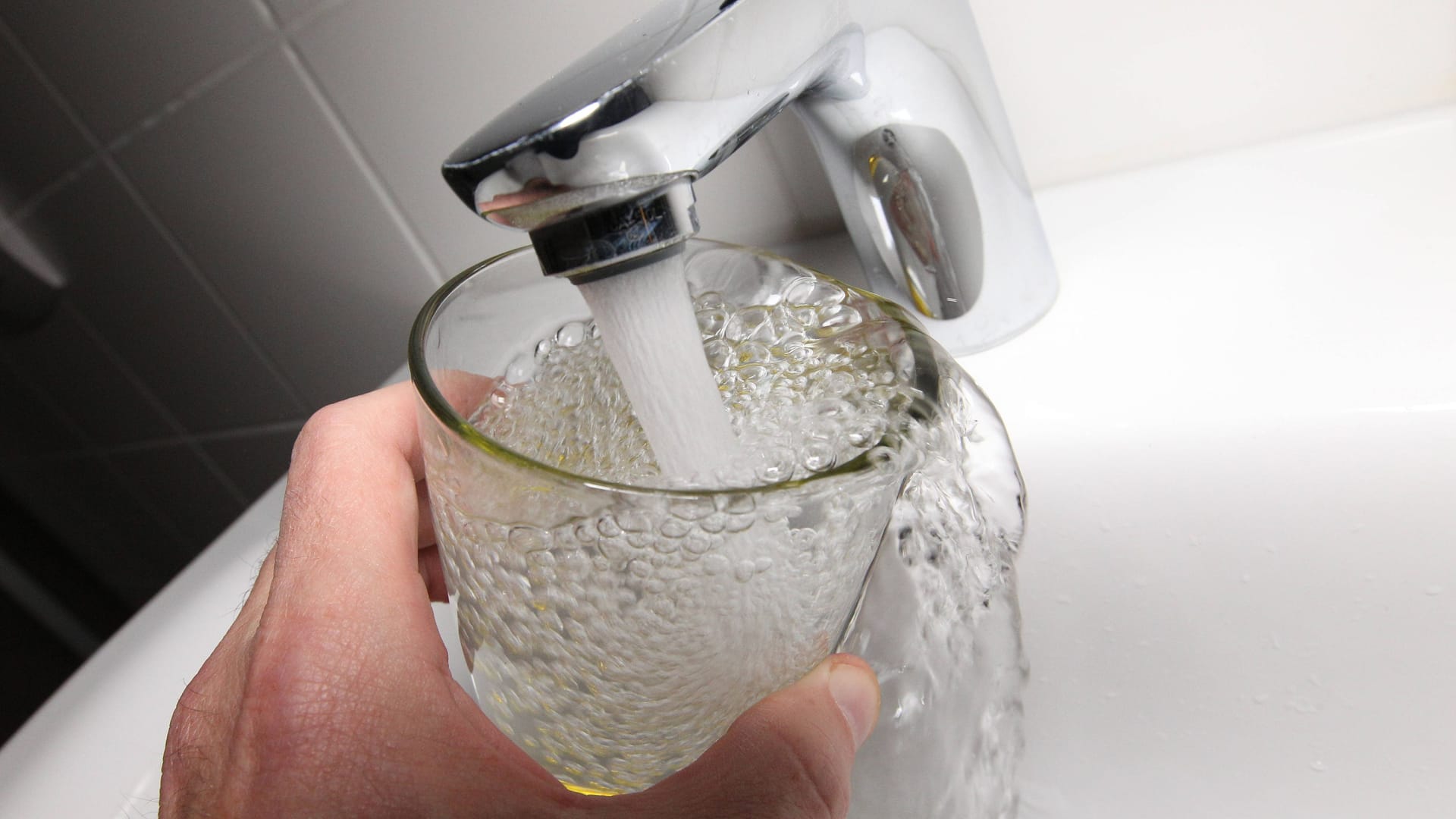 Ein Mann hält ein Glas unter einen Wasserhahn (Symbolbild): Es gab Auffälligkeiten bei einer Wasseruntersuchung.