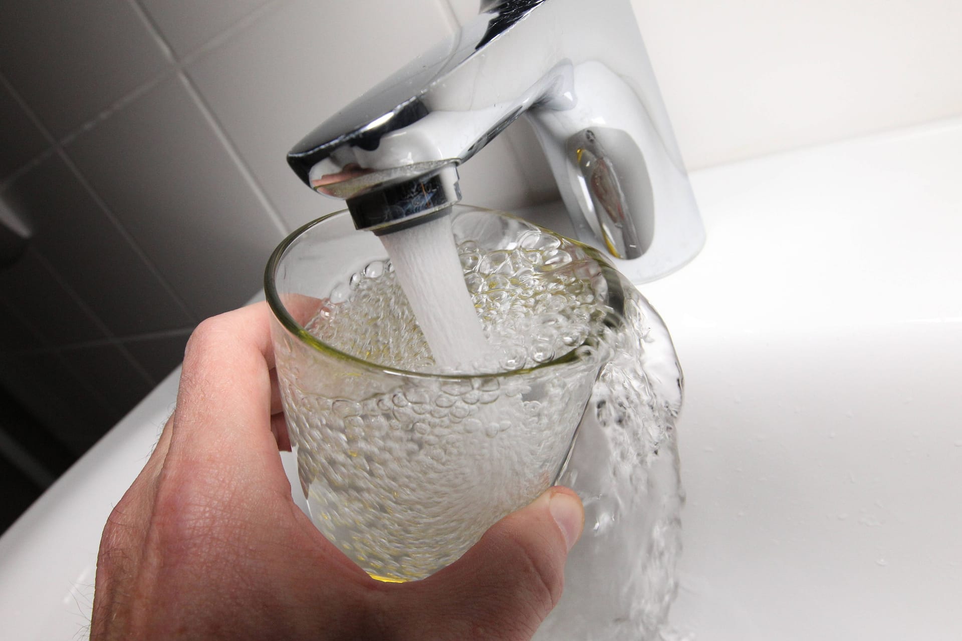 Ein Mann hält ein Glas unter einen Wasserhahn (Symbolbild): Es gab Auffälligkeiten bei einer Wasseruntersuchung. Ein Mann hält ein Glas unter einen Wasserhahn (Symbolbild): Es gab Auffälligkeiten bei einer Wasseruntersuchung.