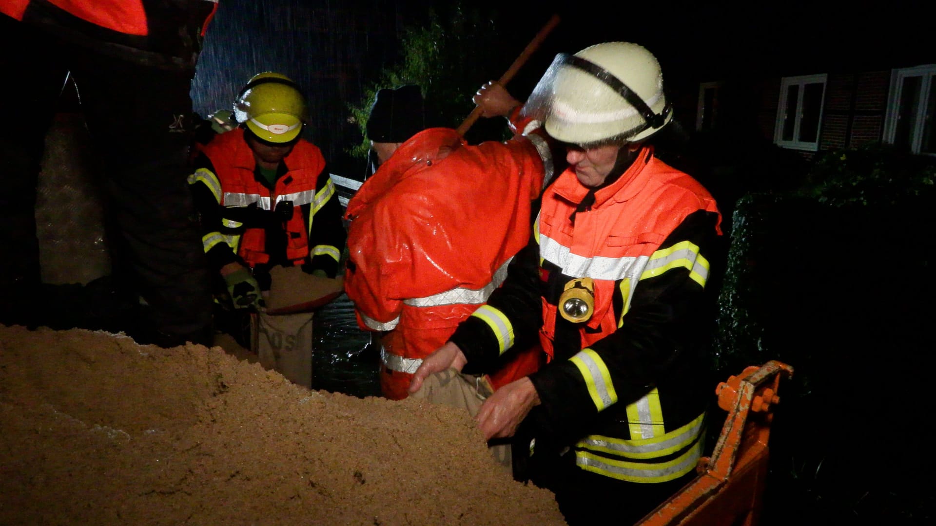 Feuerwehrleute befüllen Sandsäcke: Heftige Regenfälle sorgten im Seevetaler Ortsteil Meckelfeld für erhebliche Schäden.