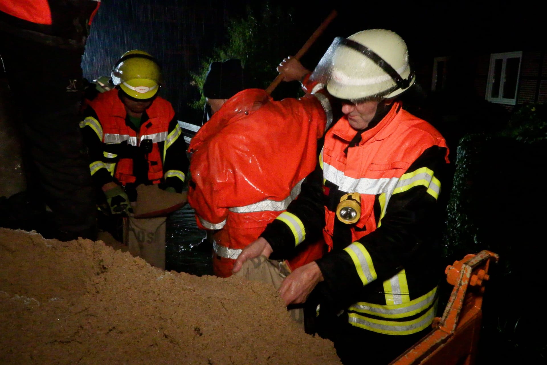 Feuerwehrleute befüllen Sandsäcke: Heftige Regenfälle sorgten im Seevetaler Ortsteil Meckelfeld für erhebliche Schäden.
