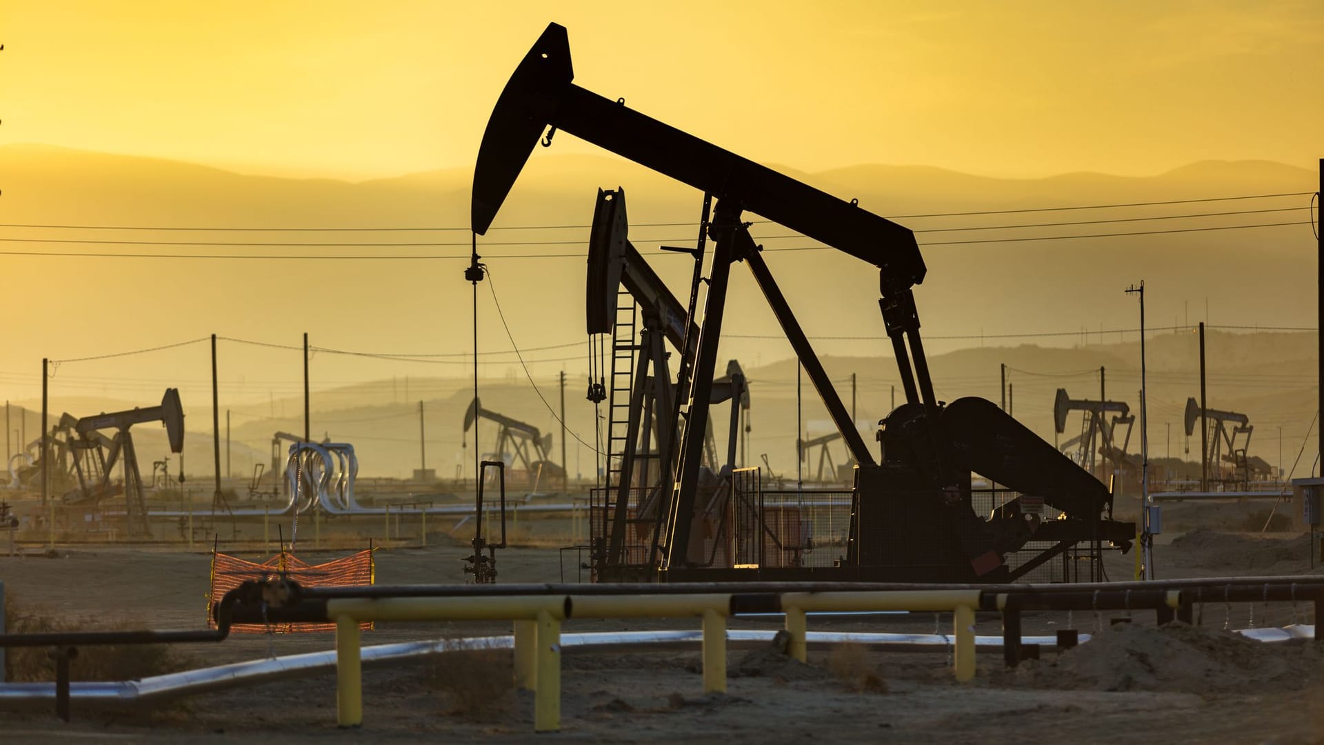 Ölpumpen vor der untergehenden Sonne im dunstigen California Central Valley in der Nähe von Bakersfield.