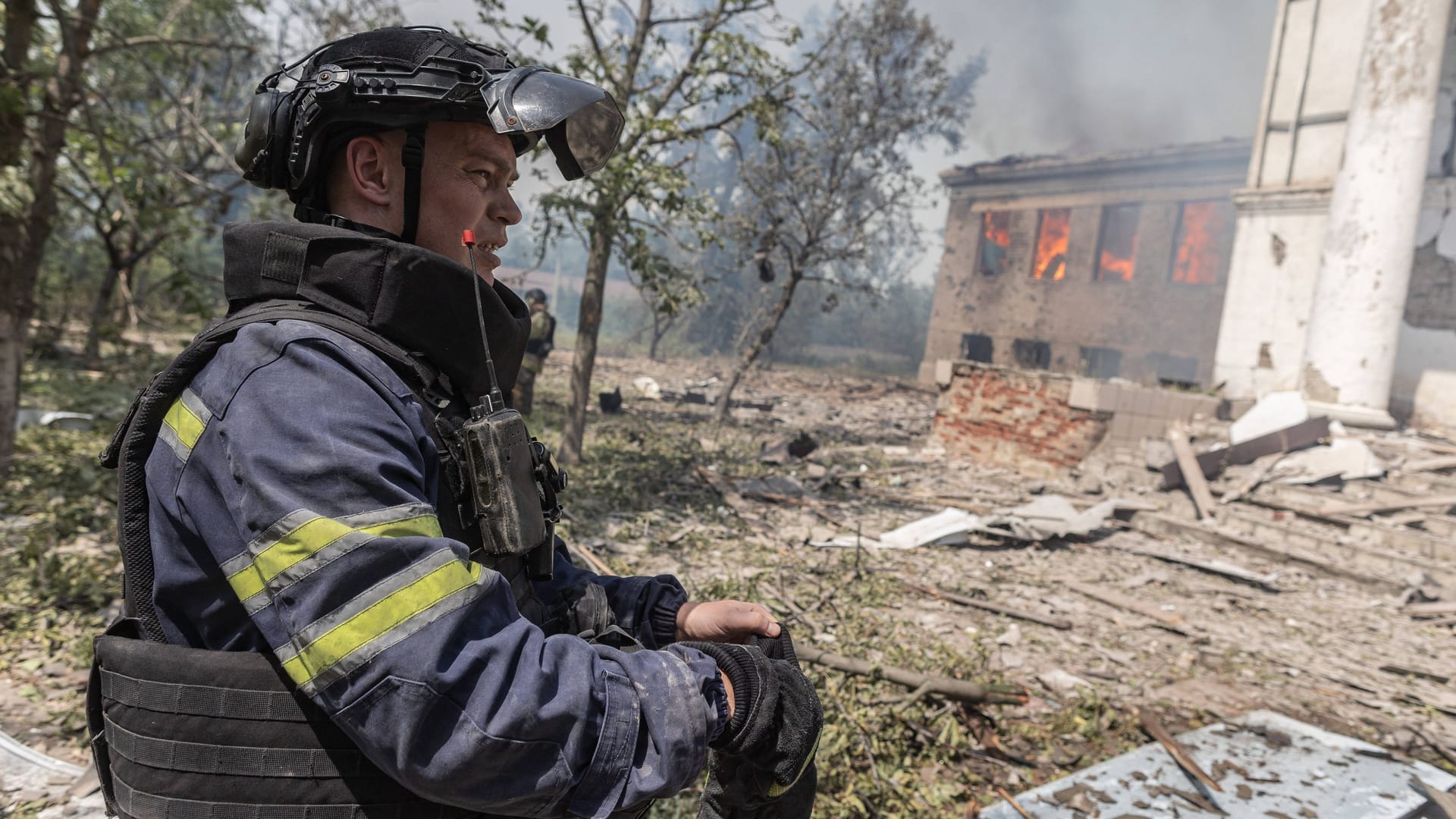 Ein ukrainischer Feuerwehrmann steht vor einer zerbombten Schule: Russland will die ukrainische Kultur weiter auslöschen.