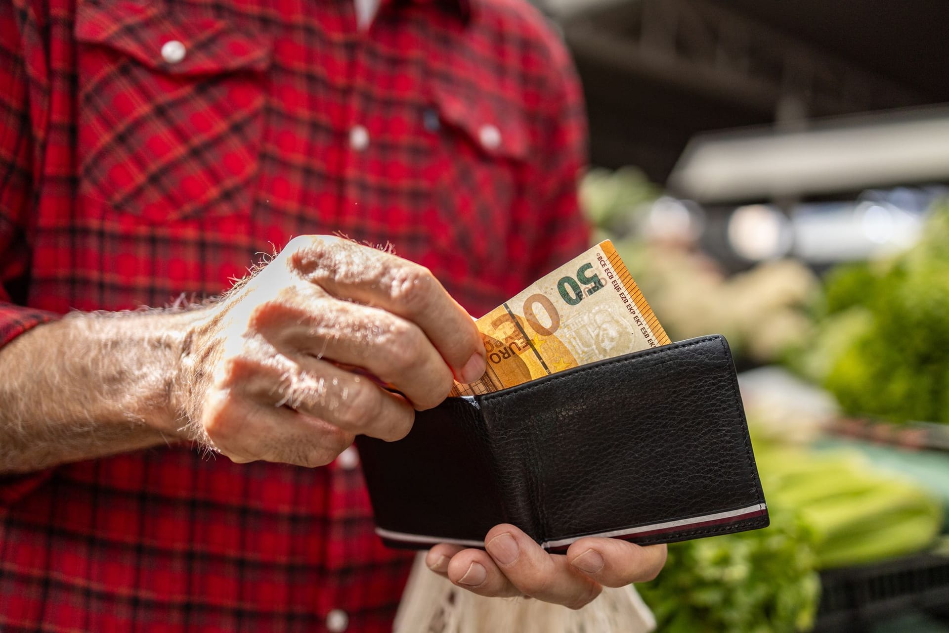 Älterer Mann zieht 50 Euro aus dem Geldbeutel: Die Rentendebatte kreist vor allem um die Frage, was es kosten darf.