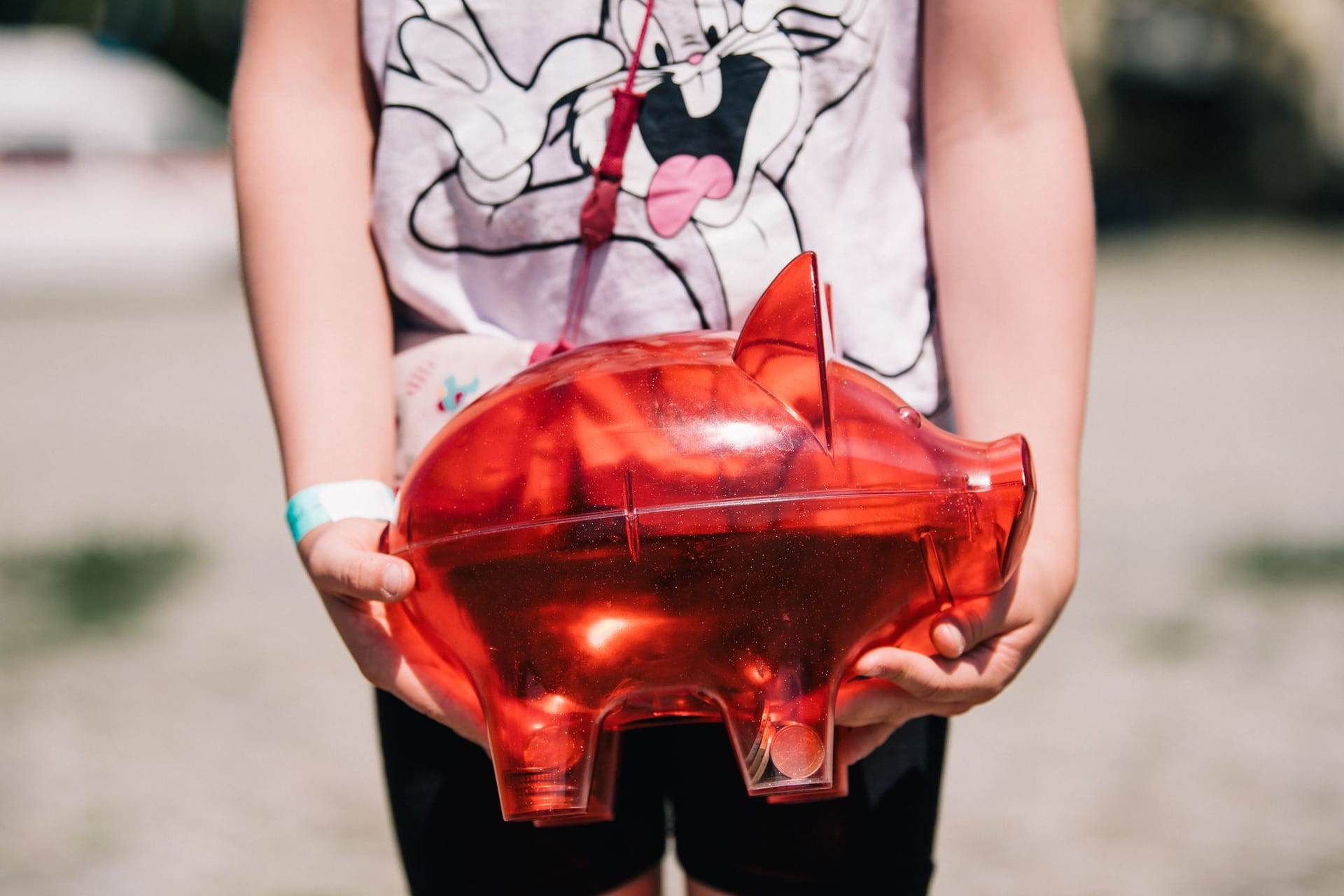 Ein Kind trägt ein rotes Sparschwein