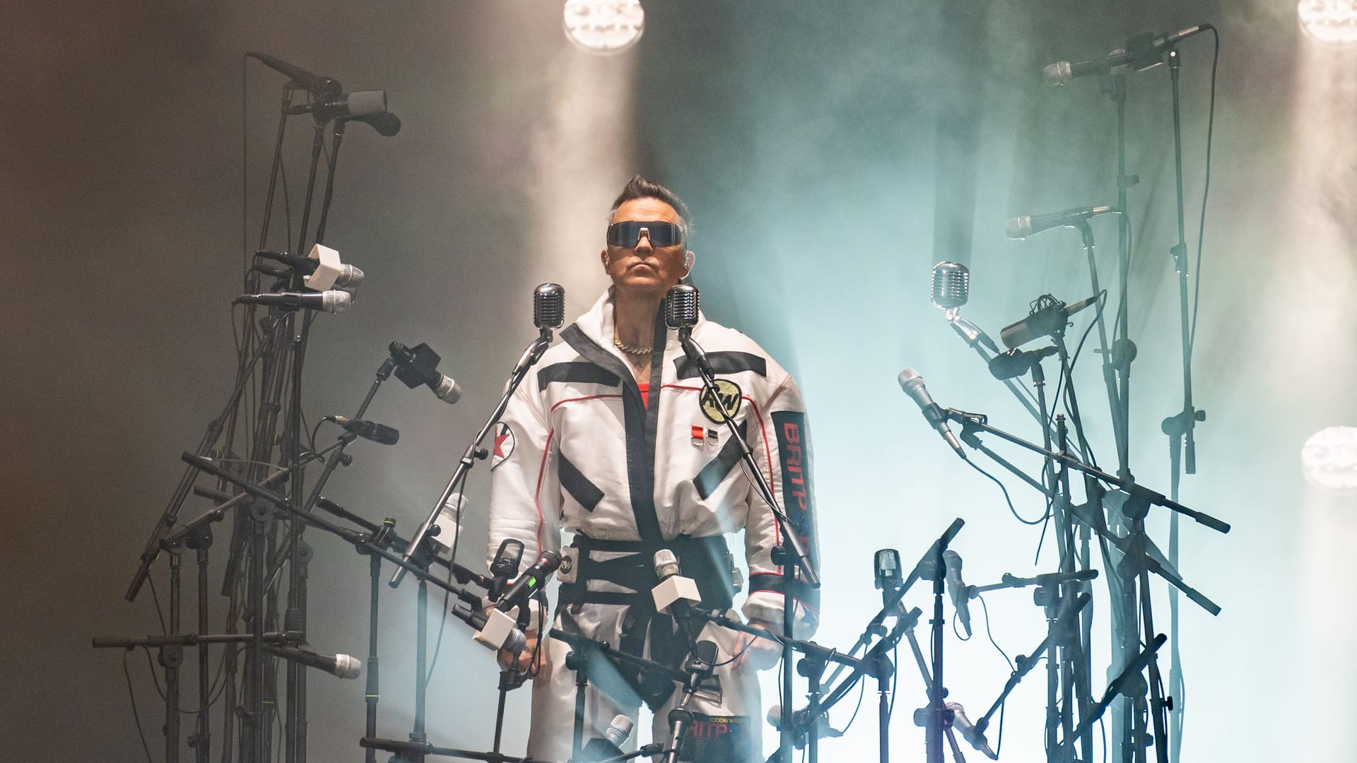 Robbie Williams umgeben von einem Meer aus Mikrofonen beim Showauftakt: Der Brite inszenierte sich direkt zum Start des Konzerts eindrucksvoll.
