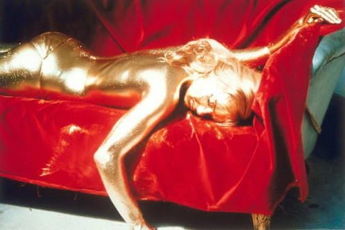 Eine Frau liegt auf dem Sofa. Sie ist vollständig mit Gold überzogen. Es handelt sich um eine Szene aus dem Film "James Bond 007 Goldfinger".