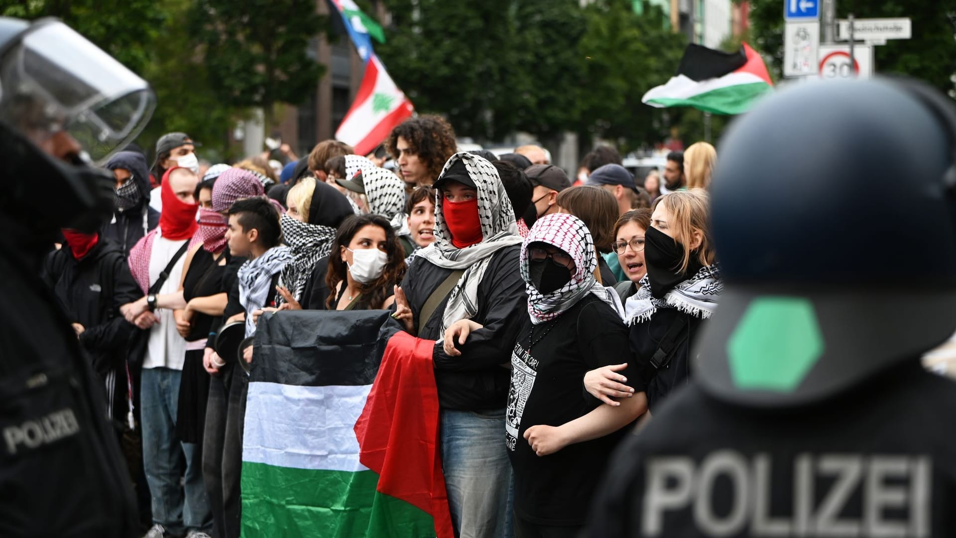 Polizisten stehen vor den Demonstranten: Mit Fahnen, Plakaten und Trommeln sind Teilnehmer einer Demonstration in Berlin unterwegs.