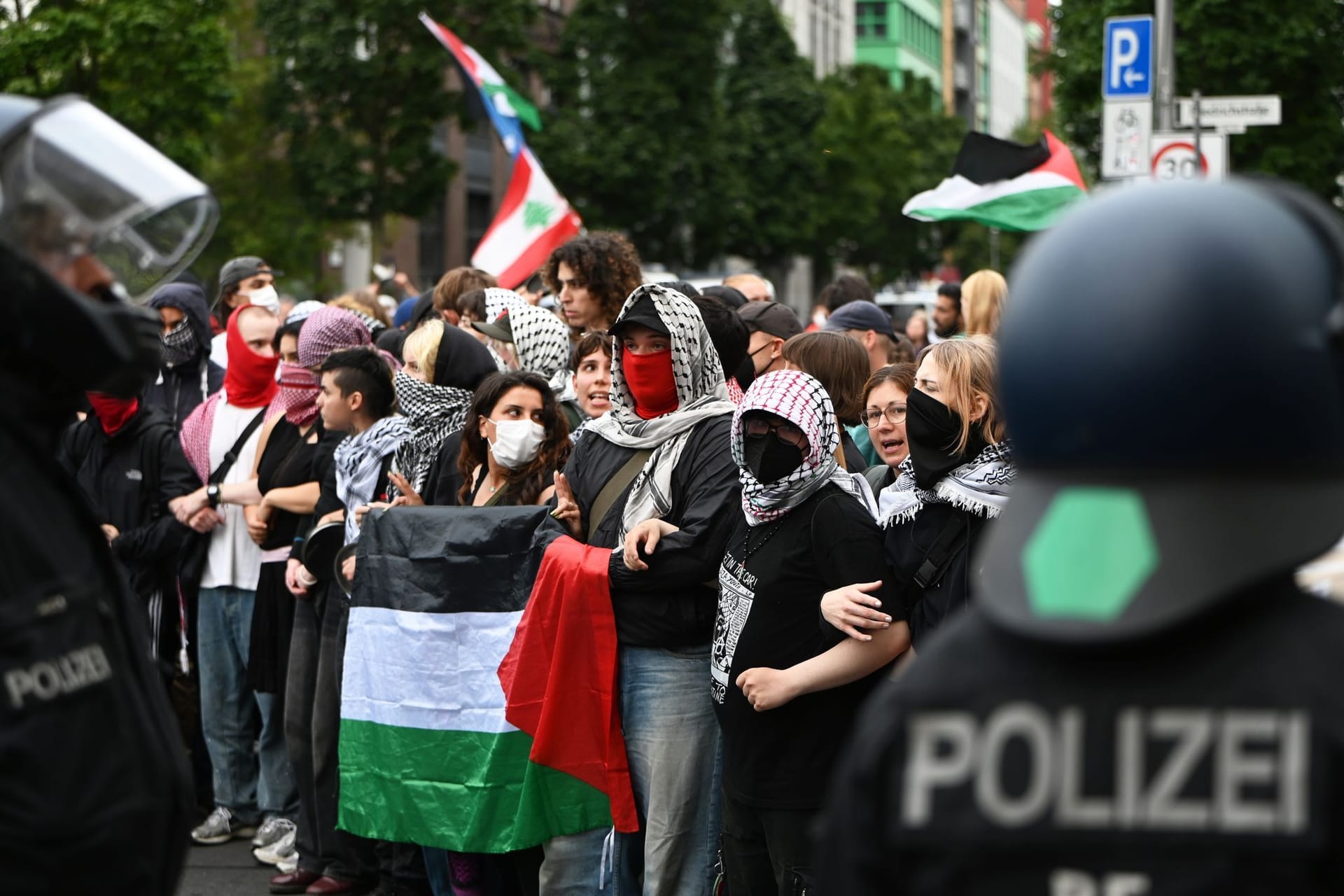Polizisten stehen vor den Demonstranten: Mit Fahnen, Plakaten und Trommeln sind Teilnehmer einer Demonstration in Berlin unterwegs.