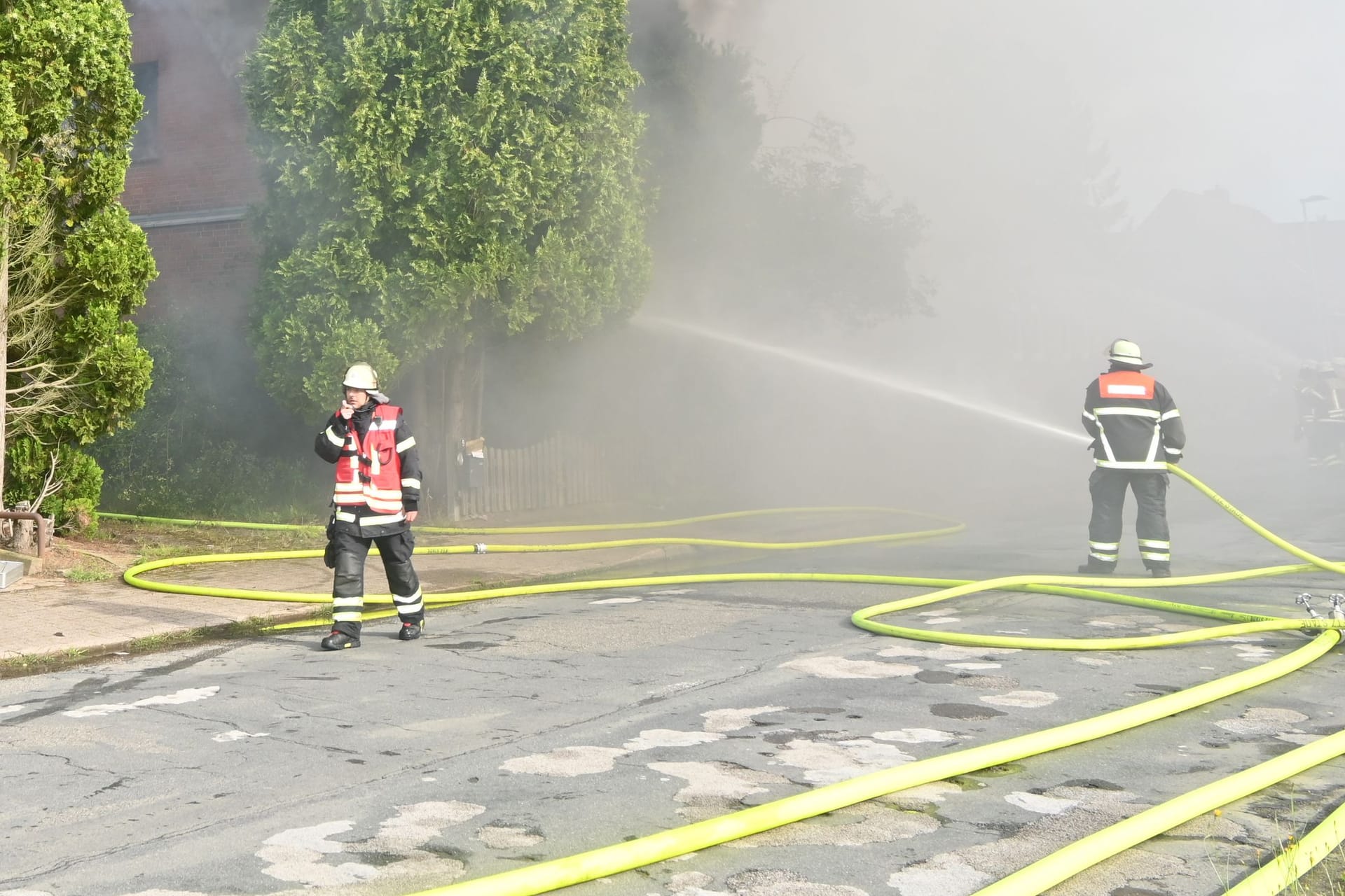 Feuerwehrleute löschen den Brand in Hollern-Twielenfleth: Eine dichte Rauchwolke zog am Mittwoch über den Ort im Alten Land hinweg.