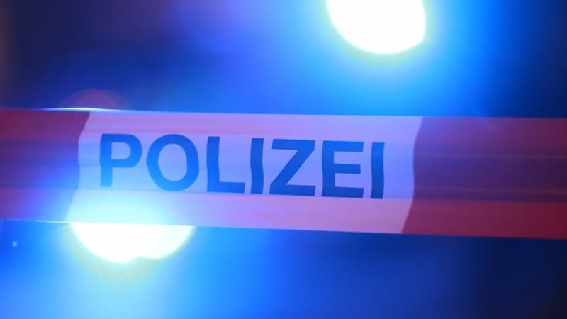 Blaulichter leuchten hinter einem Absperrband der Polizei: Blaulichter leuchten hinter einem Absperrband der Polizei: