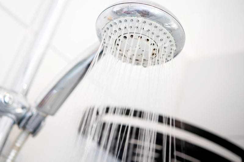 Ein Duschkopf hängt in einer Dusche in einem Badezimmer. (Symbolbild)