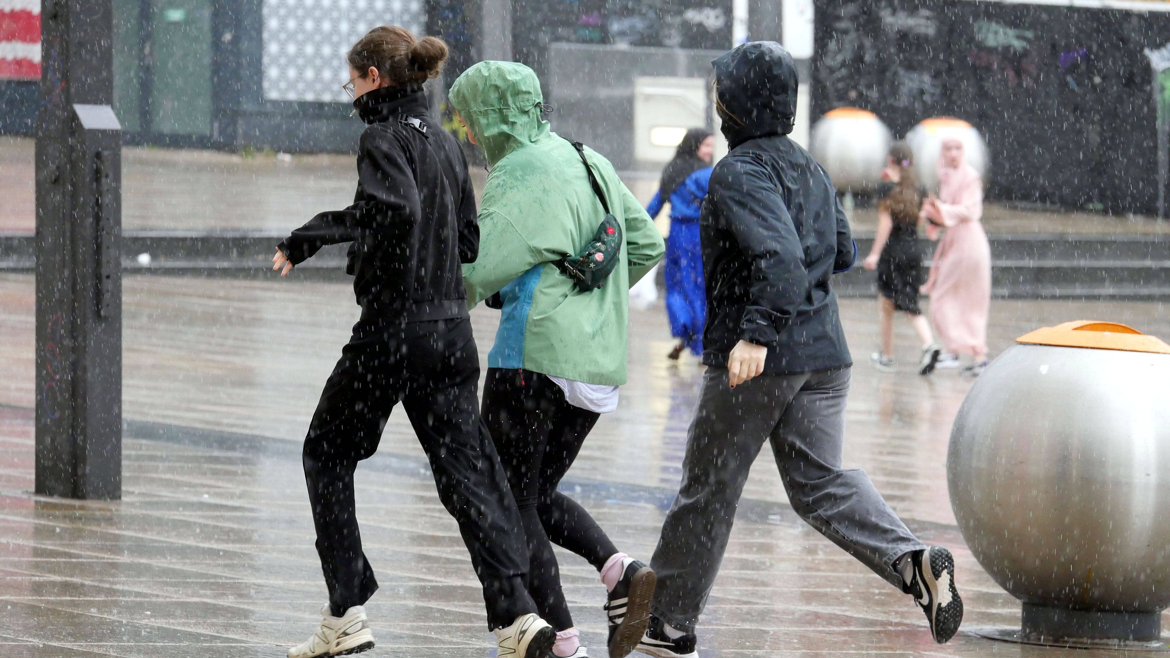 Menschen versuchen sich vor Starkregen in Sicherheit zu bringen (Symbolbild): In Rostock bedroht ein volllaufendes Rückhaltebecken ein Wohngebiet.