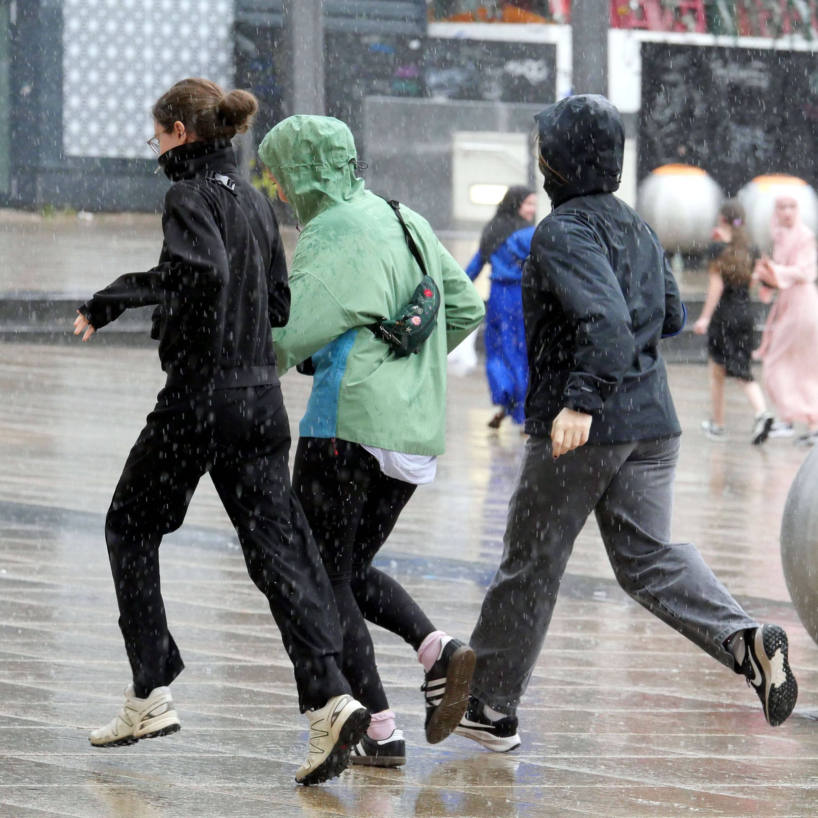 Menschen versuchen sich vor Starkregen in Sicherheit zu bringen (Symbolbild): In Rostock bedroht ein volllaufendes Rückhaltebecken ein Wohngebiet.
