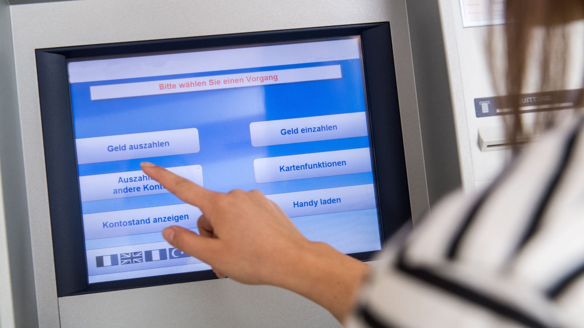 Frau hebt Geld an einem Automaten ab Frau hebt Geld an einem Automaten ab