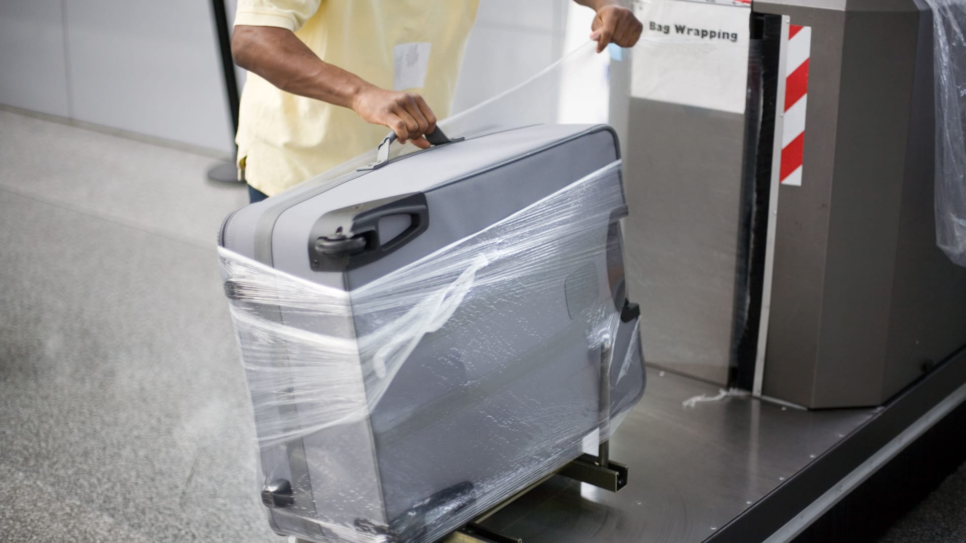Ein Flughafenangestellter wickelt Plastikfolie um einen Koffer (Archivbild): Am HAJ können folierte Koffer nicht aufgegeben werden.