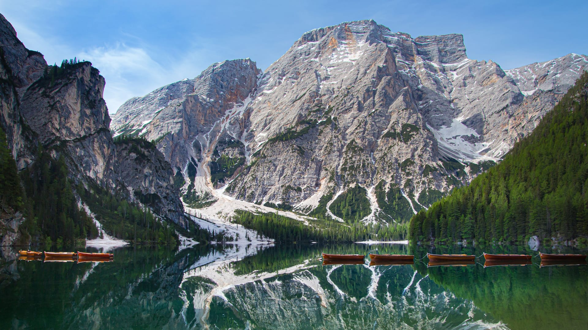 Mount Seekofel and boats mirroring in the clear water of mountain lake Pragser Wildsee