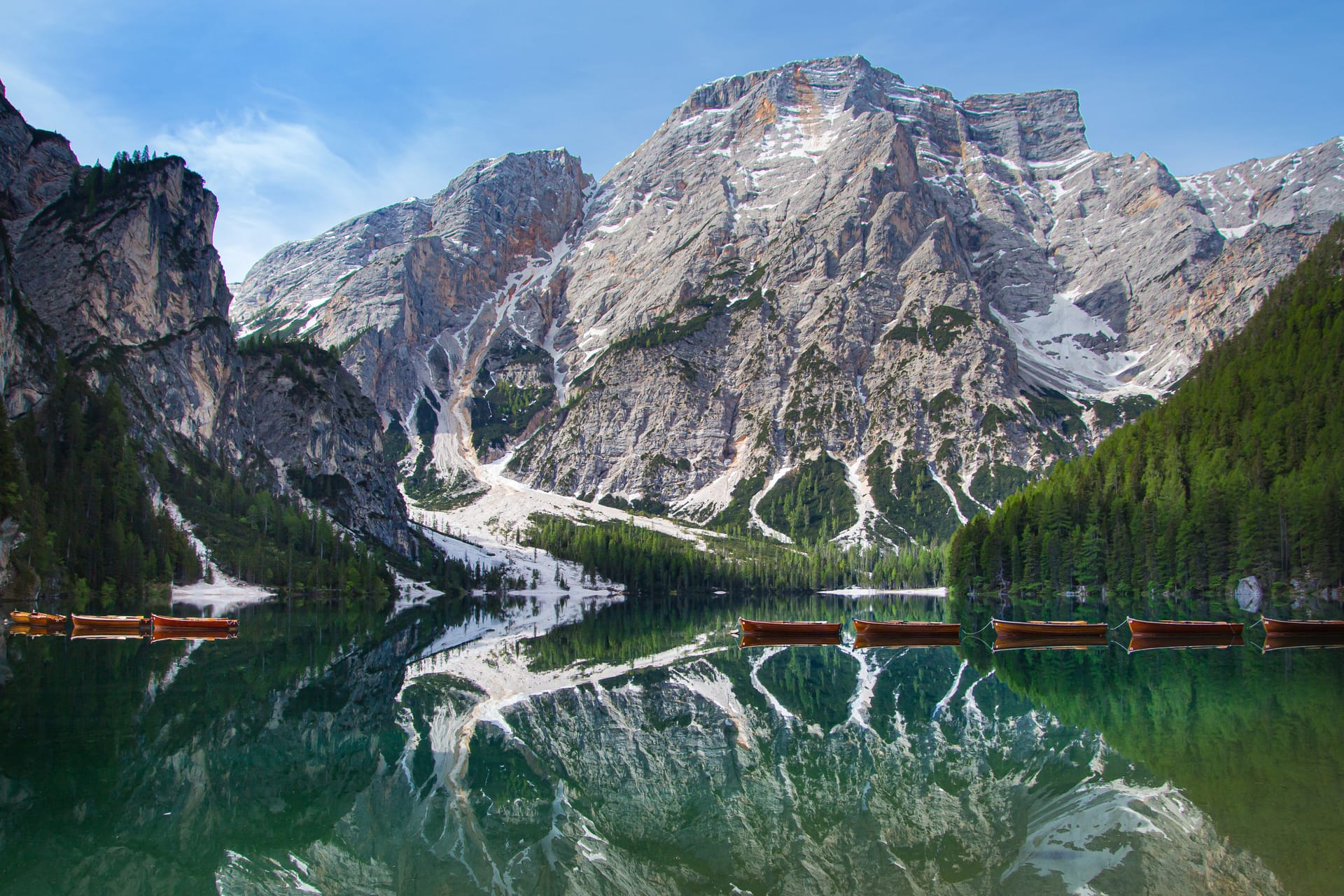Mount Seekofel and boats mirroring in the clear water of mountain lake Pragser Wildsee