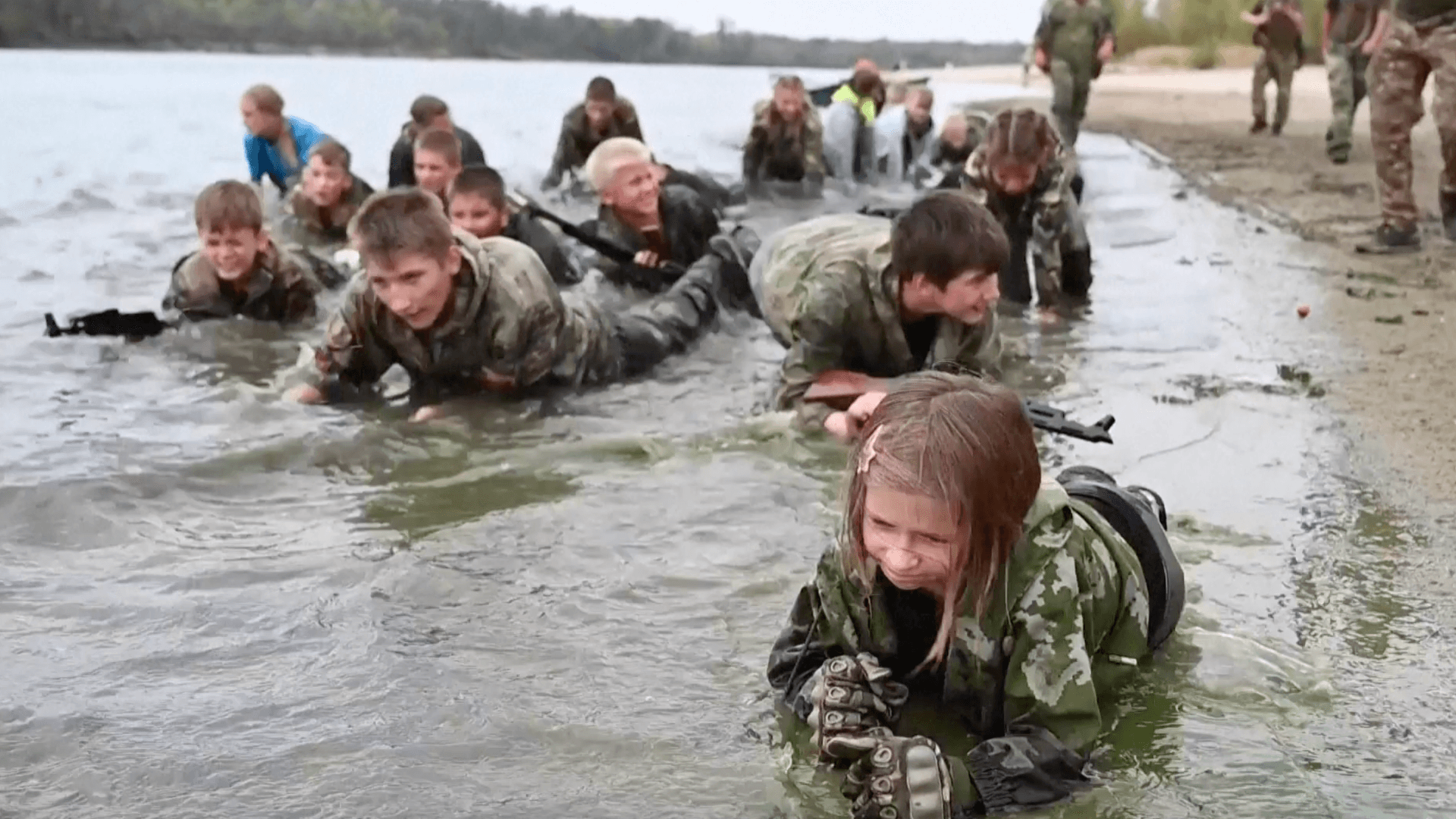 Russische Kinder robben bei einem Militärbootcamp in der Region Rostow durch Schlamm.