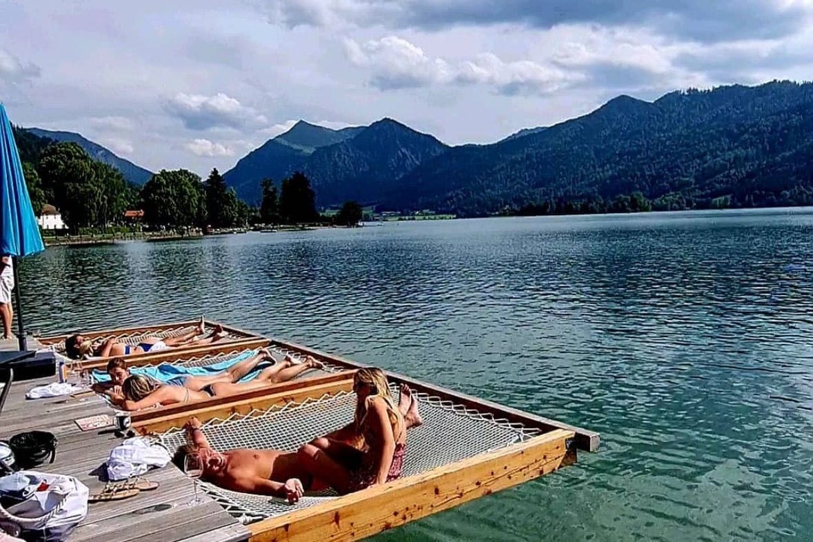 Auf netzartigen Liegen im Wasser des Schliersees fühlt sich der Sommer in München wie Urlaub an.