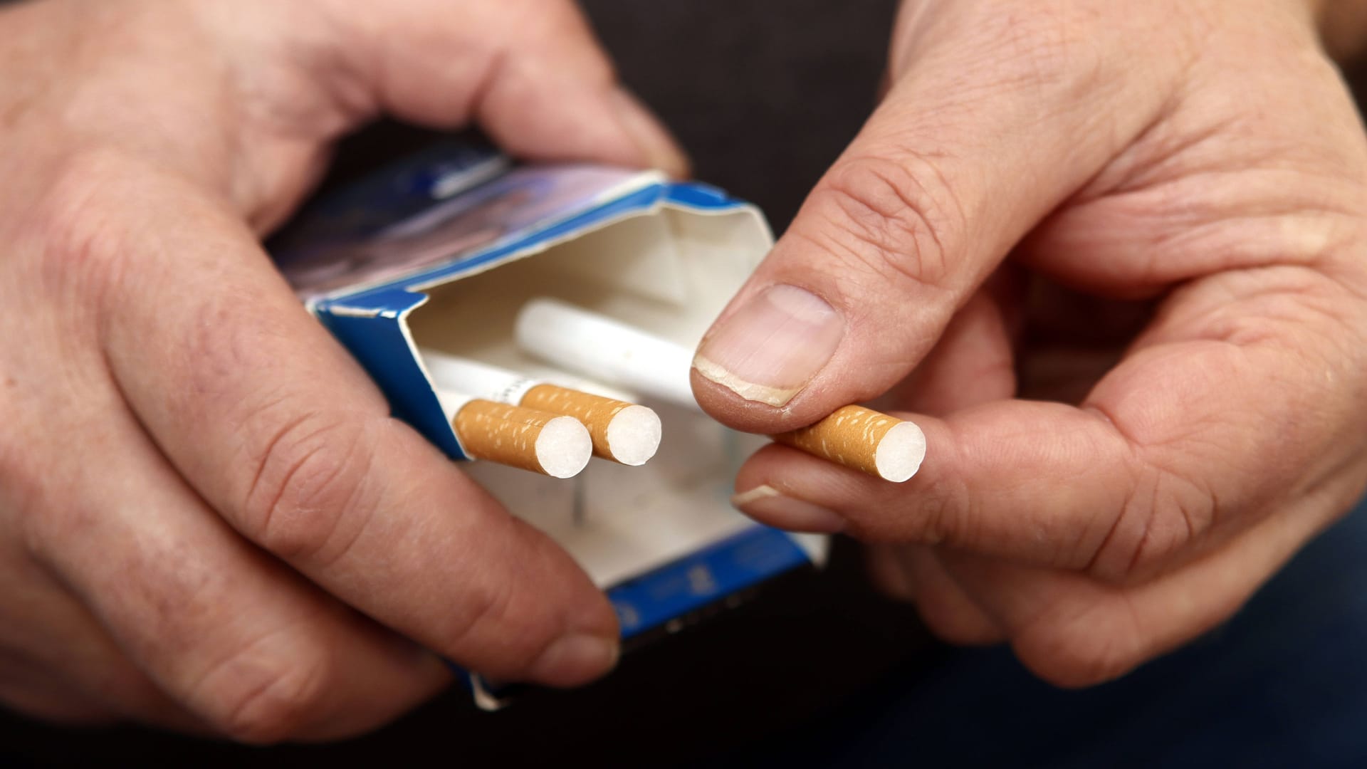 Mann hält Zigarettenschachtel in der Hand