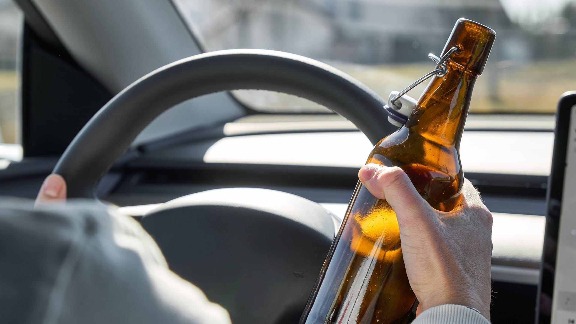 Ein Mann hält eine Bierflasche in der Hand, während er am Steuer sitzt (Symbolbild): Ein Lkw-Fahrer muss nach einer Trunkenheitsfahrt mit Konsequenzen rechnen. Ein Mann hält eine Bierflasche in der Hand, während er am Steuer sitzt (Symbolbild): Ein Lkw-Fahrer muss nach einer Trunkenheitsfahrt mit Konsequenzen rechnen.