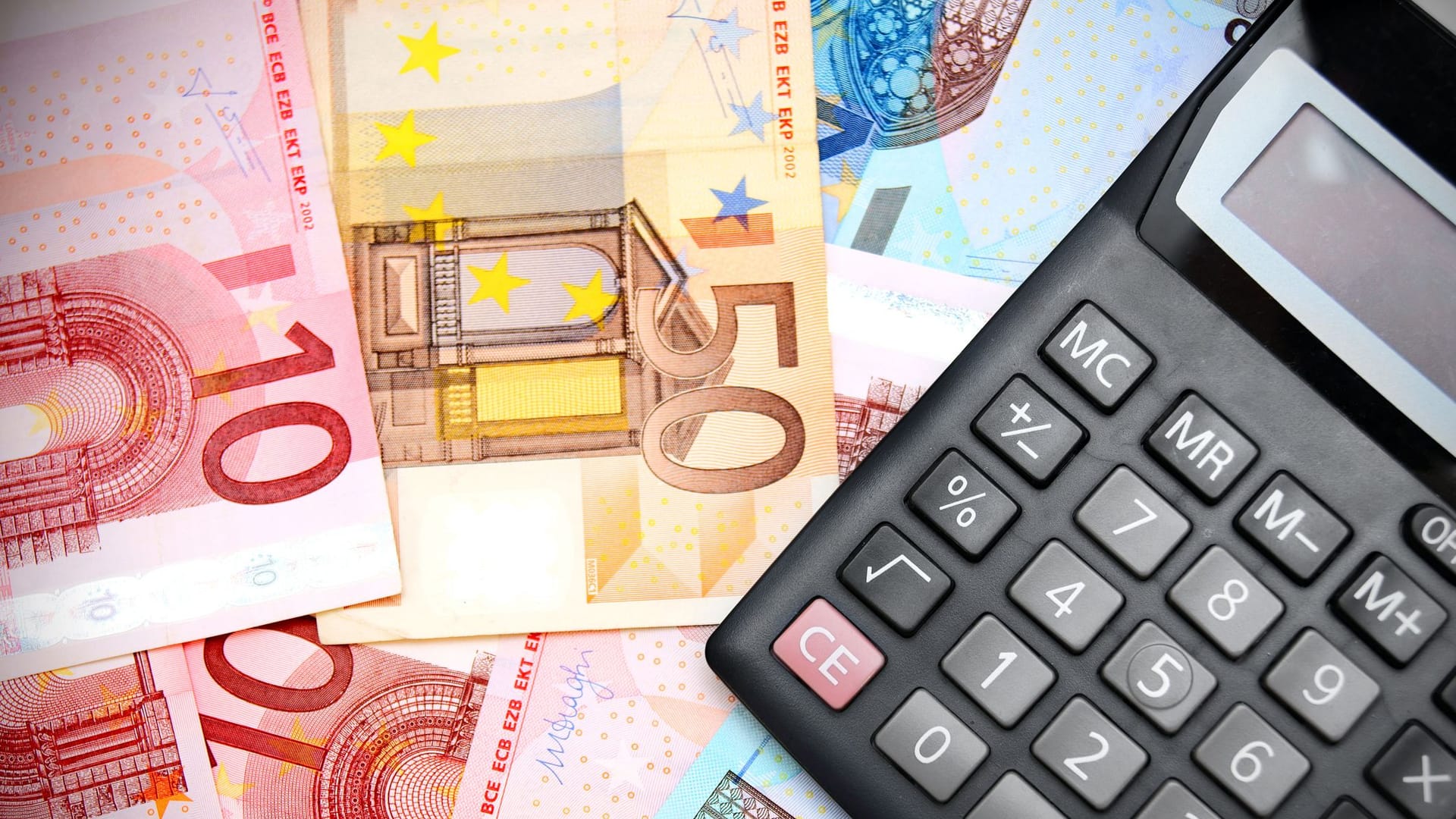 Euro-Banknoten und Taschenrechner liegen auf einem Tisch Euro-Banknoten und Taschenrechner liegen auf einem Tisch