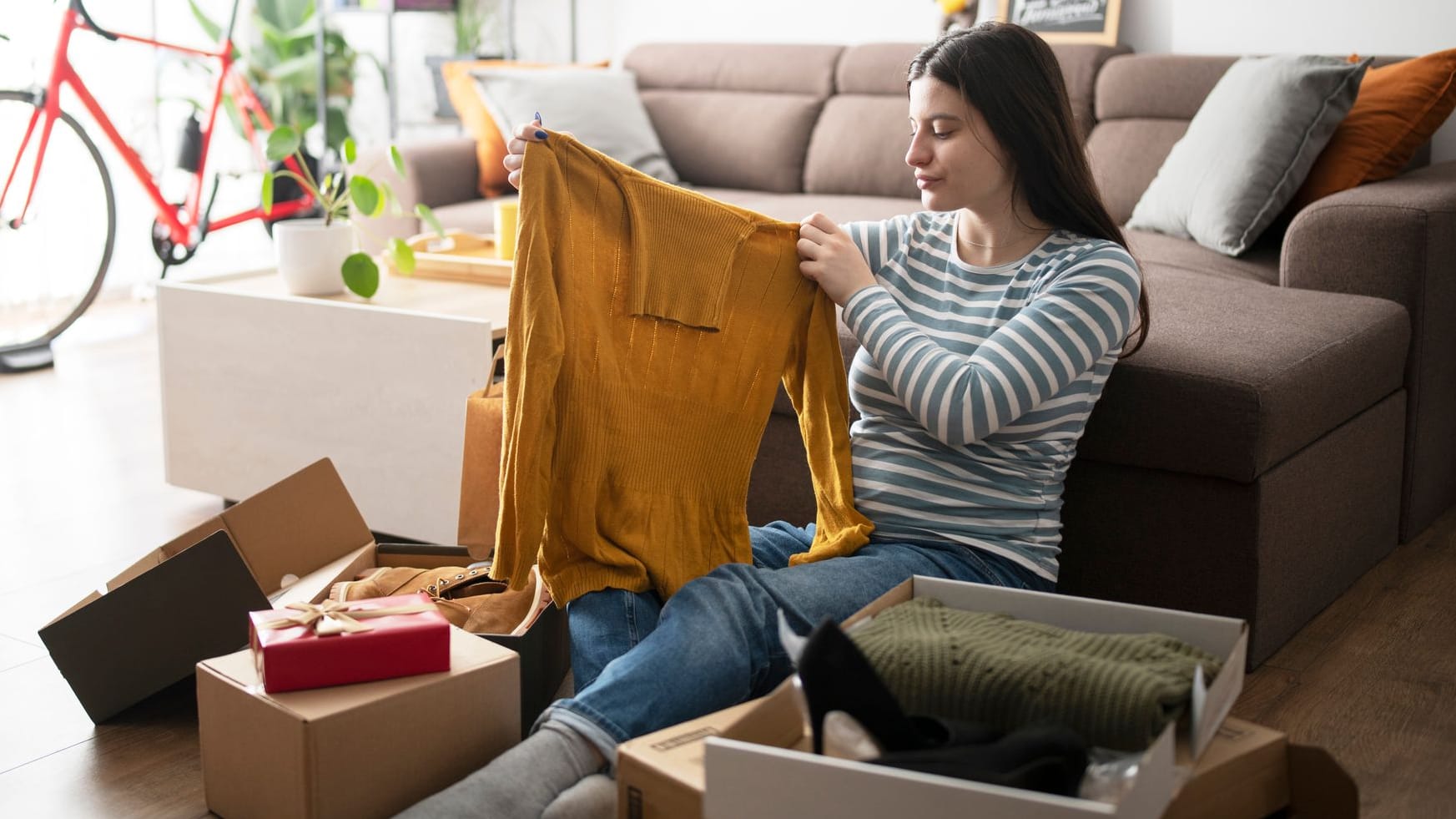 Junge Frau sitzt auf dem Fußboden und packt Pakete aus Junge Frau sitzt auf dem Fußboden und packt Pakete aus