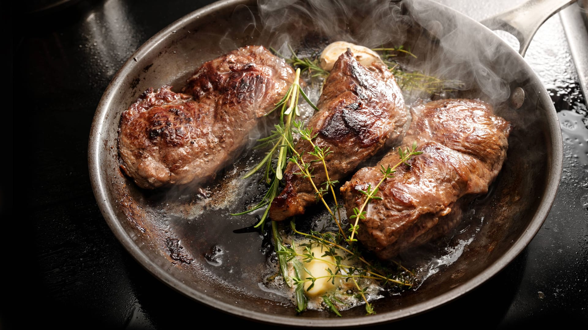 Zisch: Steaks mit ein paar Stengeln Thymian brutzeln in der Pfanne.