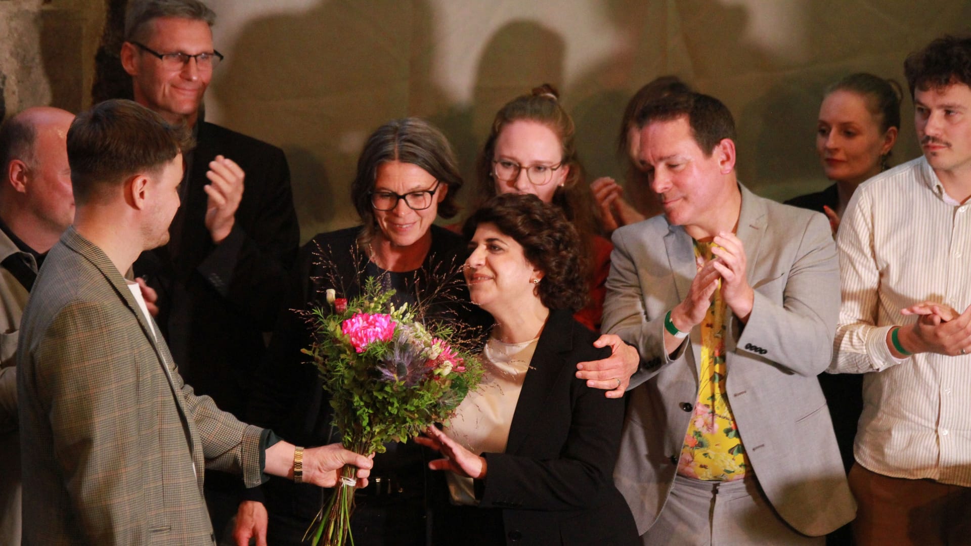 Aymaz wird unter Applaus auf der Bühne empfangen.