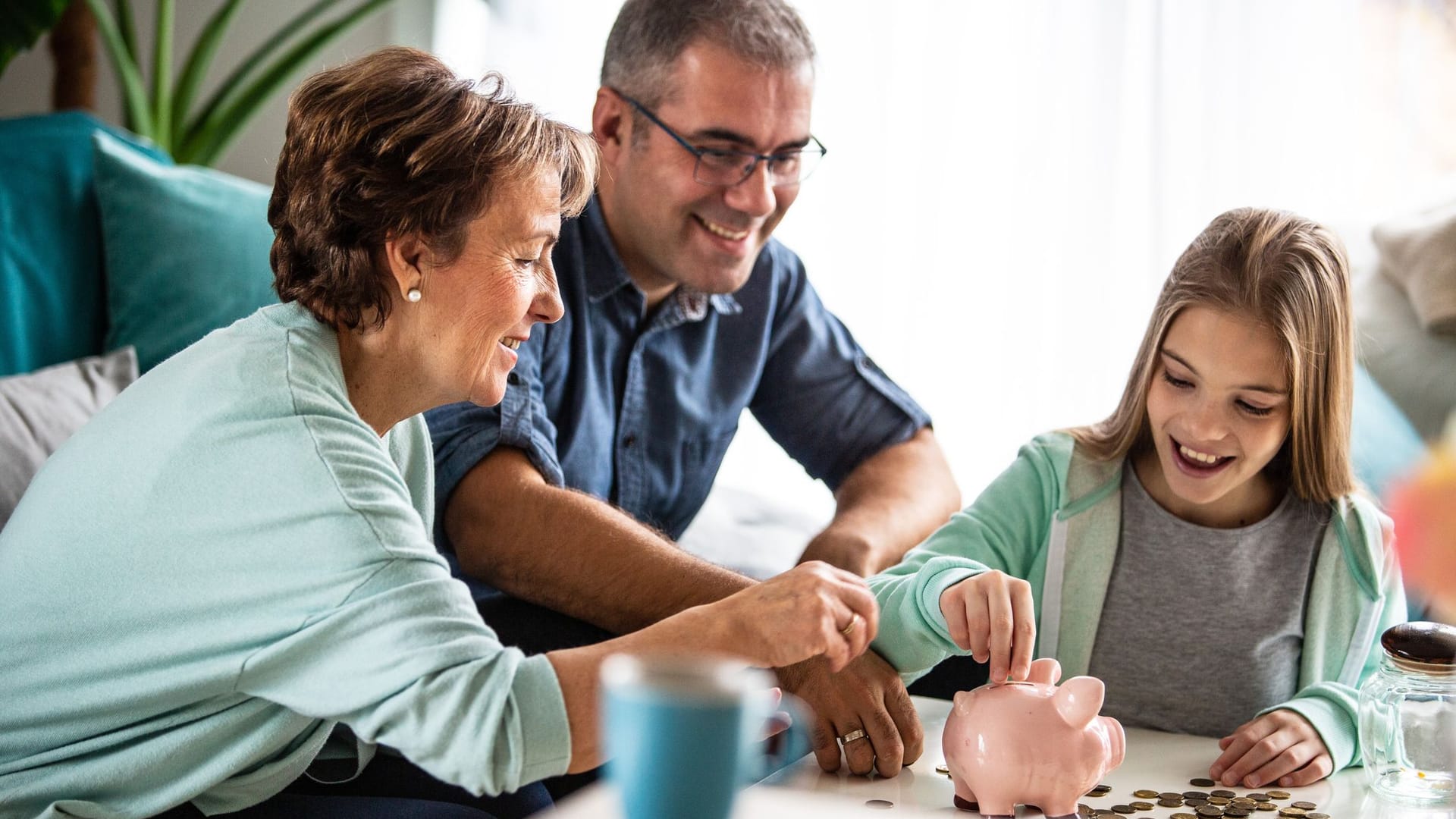 Eltern und Großeltern sparen gemeinsam mit dem Kind Geld in einer Spardose Eltern und Großeltern sparen gemeinsam mit dem Kind Geld in einer Spardose