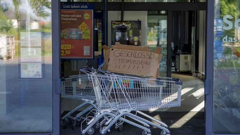 Im Eingang eines Supermarkts steht ein Einkaufswagen mit einer Pappe mit der Aufschrift "Geschlossen Stromausfall". Im Eingang eines Supermarkts steht ein Einkaufswagen mit einer Pappe mit der Aufschrift "Geschlossen Stromausfall".