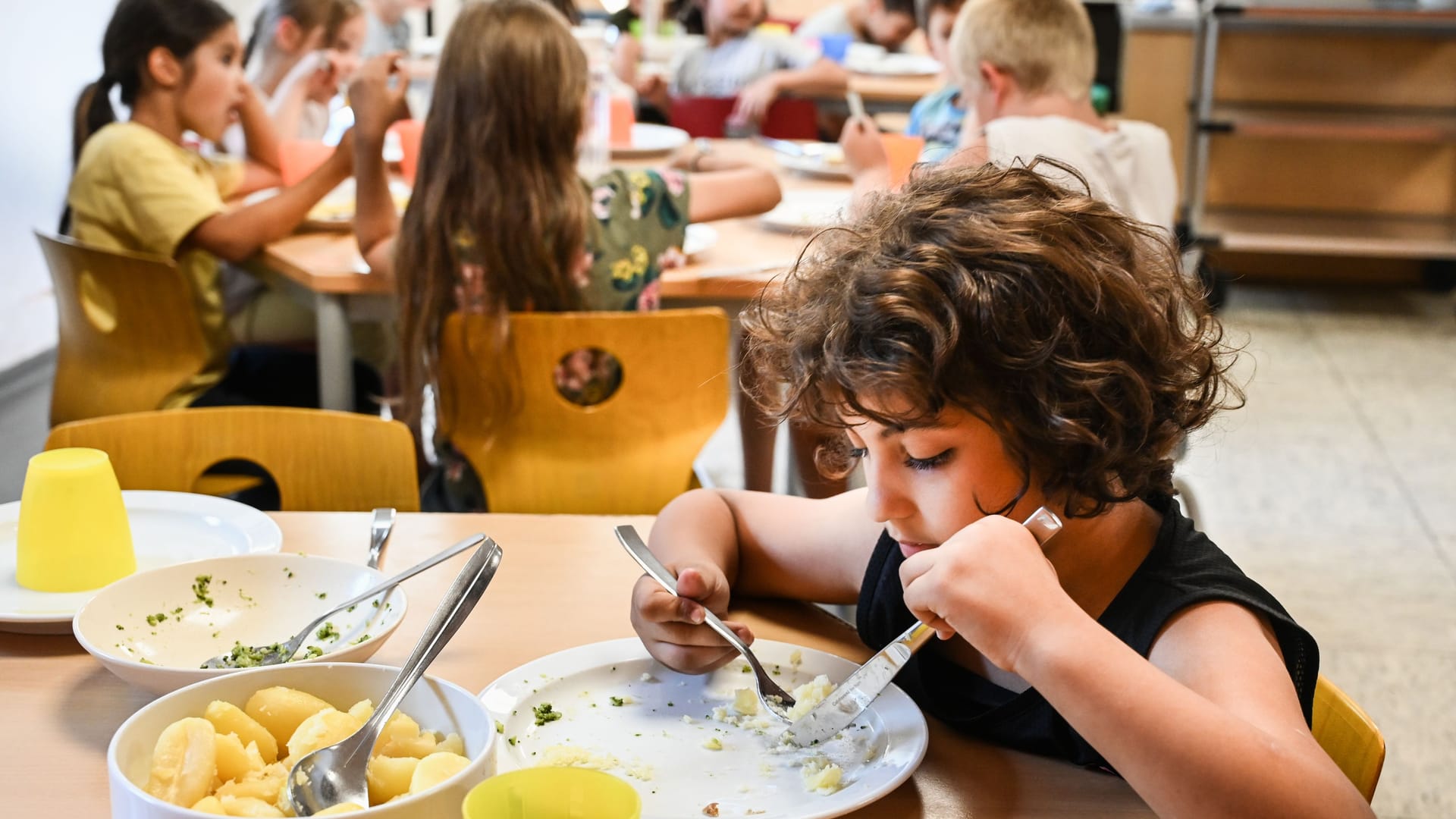 Kinder essen in der Mensa einer Grundschule (Symbolfoto): In Braunschweig soll künftig niemand vom Mittagessen ausgeschlossen werden.