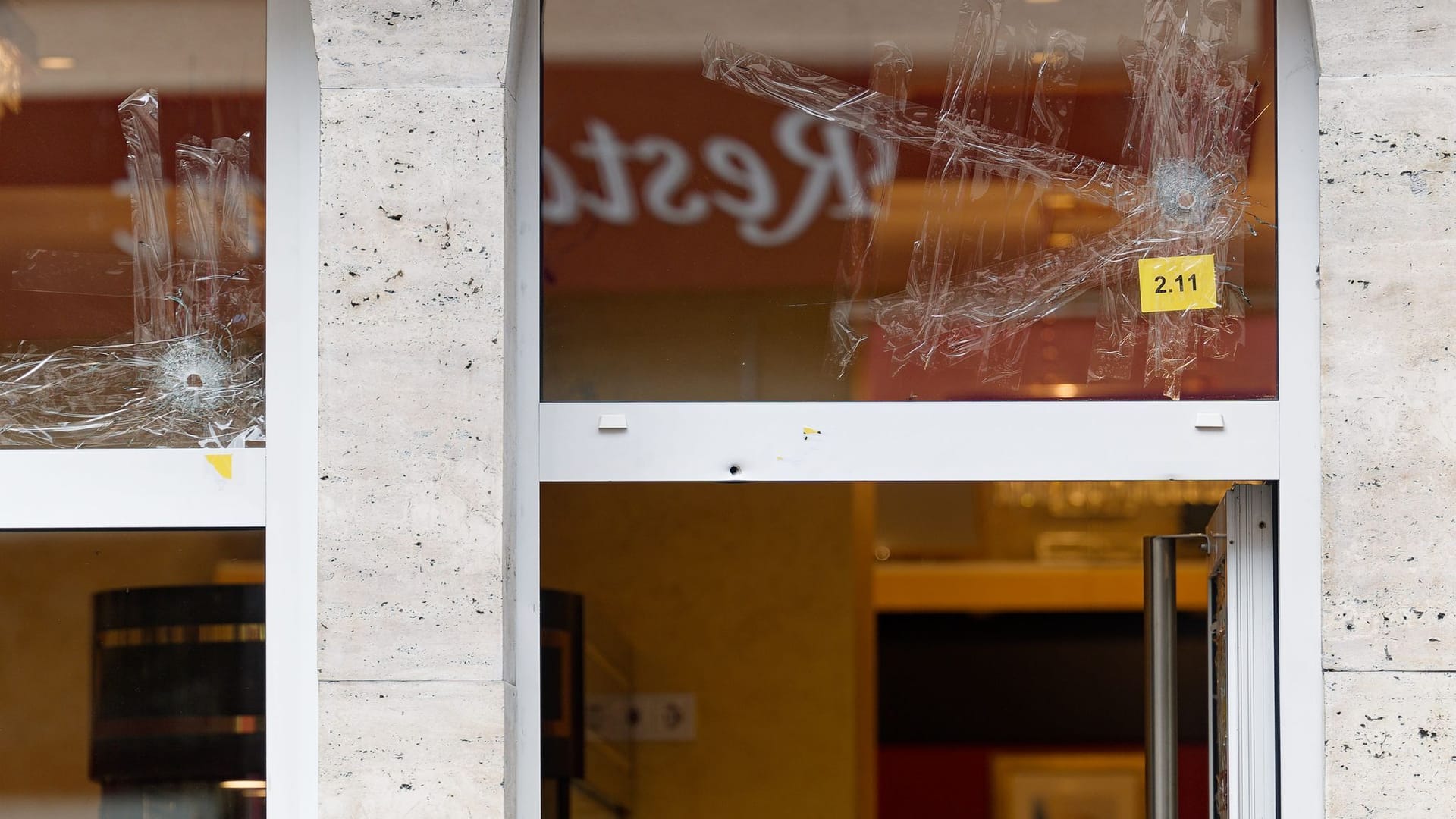 Einschusslöcher in einem Fenster über dem Eingang zu einer Konditorei zu sehen: Der mutmaßliche Schütze wurde festgenommen. Einschusslöcher in einem Fenster über dem Eingang zu einer Konditorei zu sehen: Der mutmaßliche Schütze wurde festgenommen.