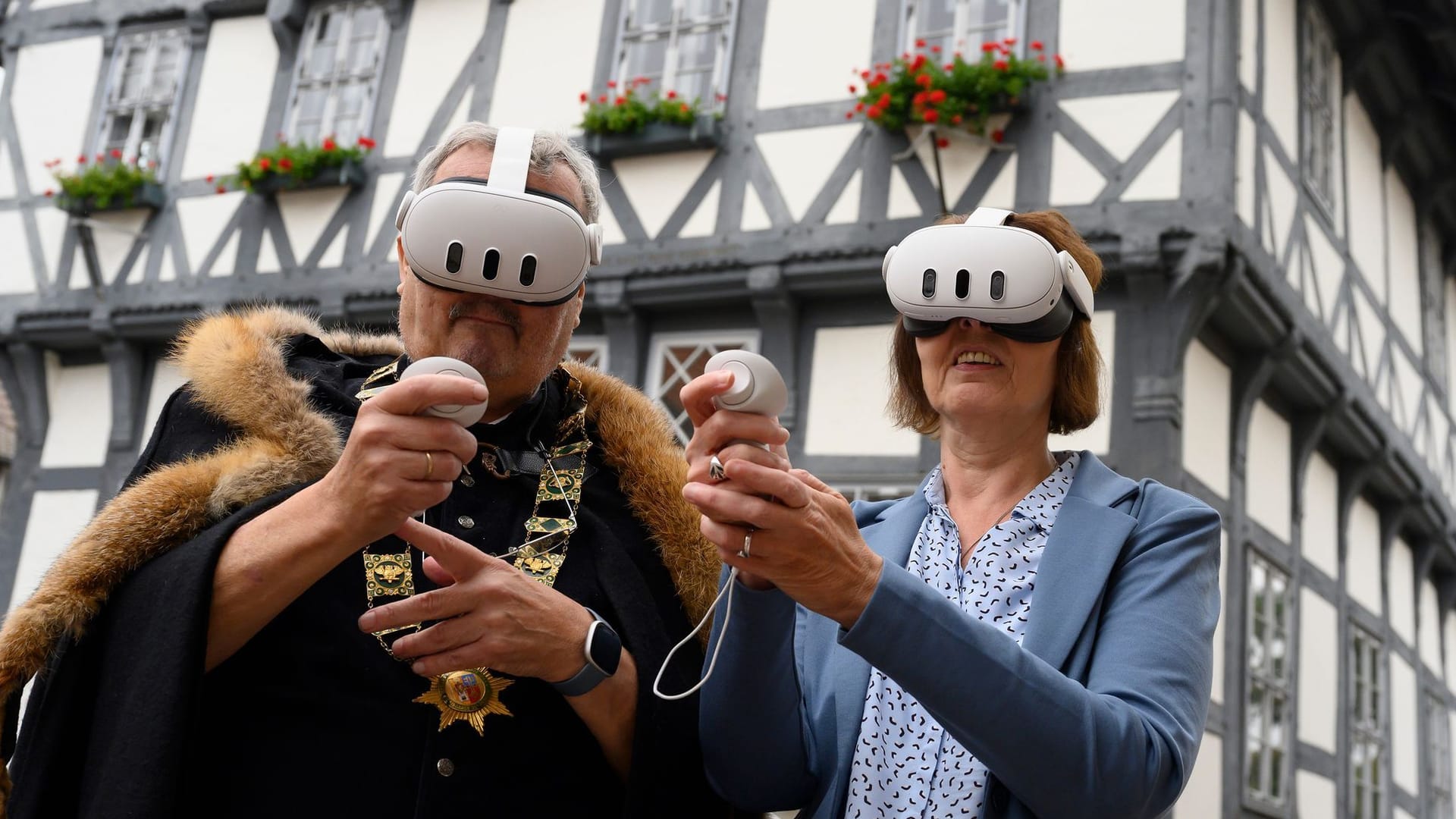 Jürgen Fischer, als Erich II. kostümierter Stadtführer, und Claudia Filpe, Mitarbeiterin der Touristik-Information Uslar, tragen vor dem Rathaus der Stadt Virtual-Reality-Brillen.