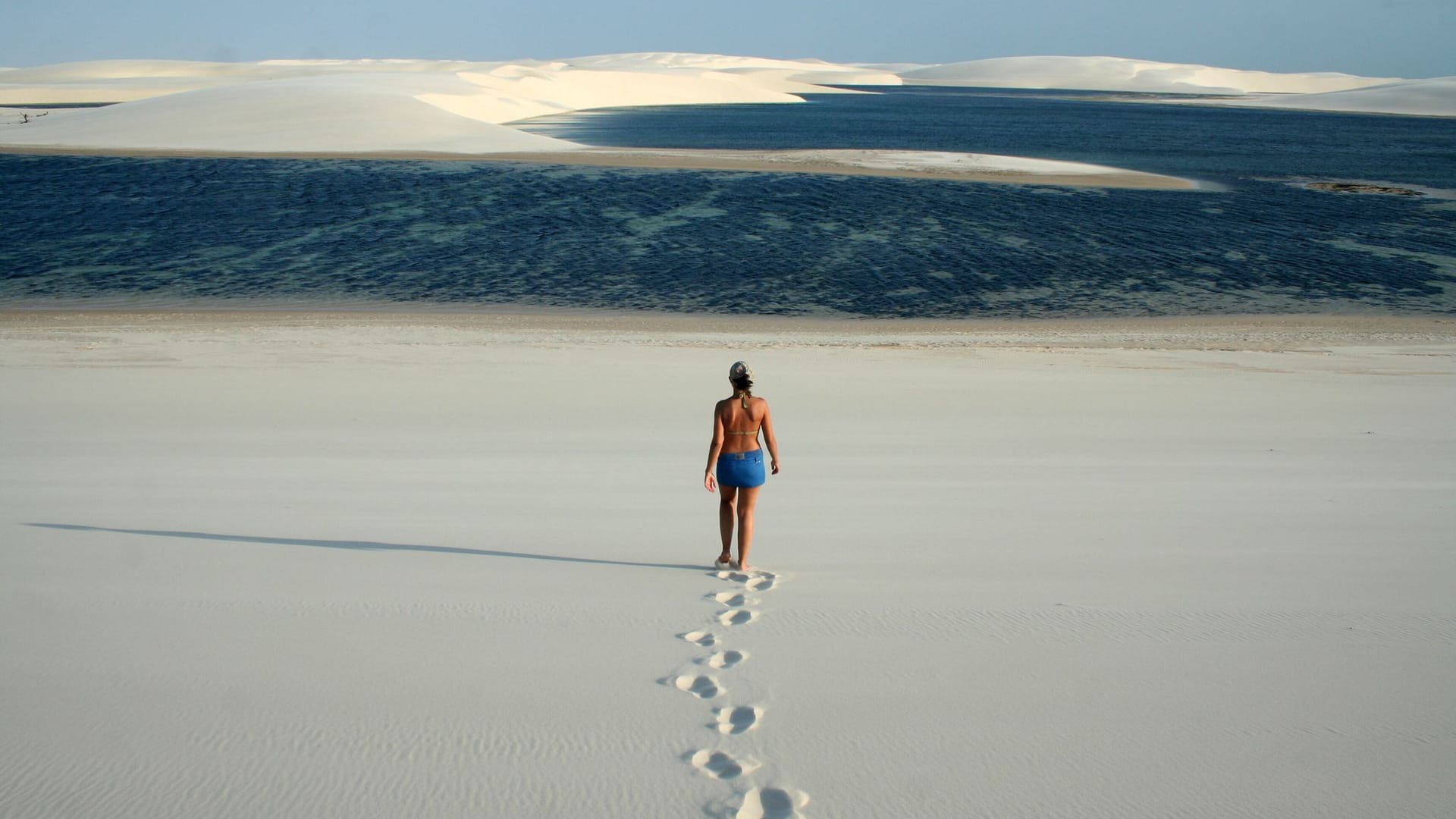 Frau läuft durch Dünenlandschaft zu einer kleinen Lagune
