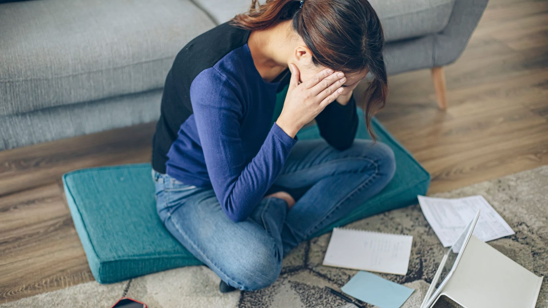Frau sitzt auf dem Fußboden und versucht Ordnung in ihre Finanzen zu bringen Frau sitzt auf dem Fußboden und versucht Ordnung in ihre Finanzen zu bringen