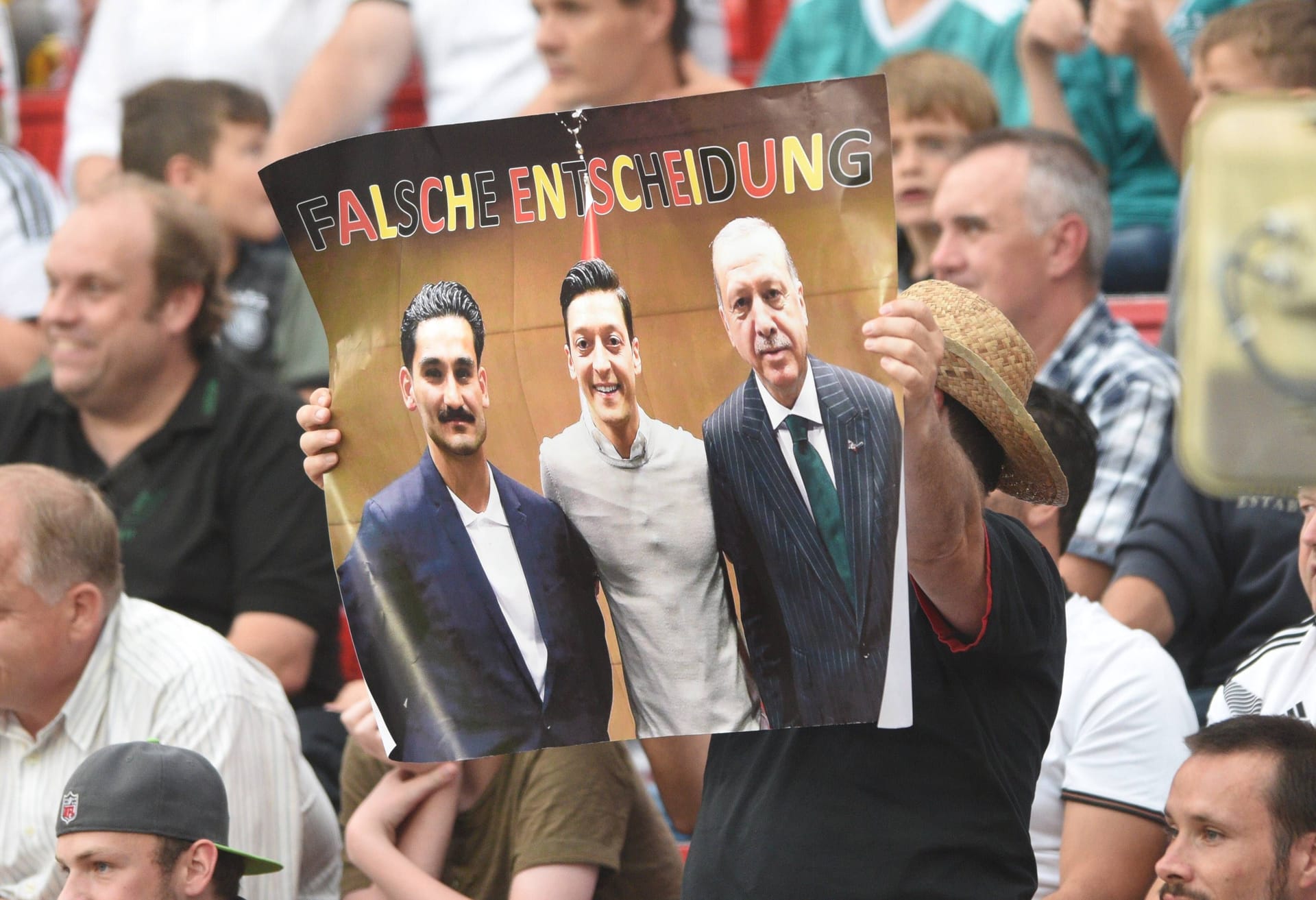 Ein Protestplakat eines Fans zeigt das viel diskutierte Foto der Nationalspieler mit dem türkischen Präsidenten. Ein Protestplakat eines Fans zeigt das viel diskutierte Foto der Nationalspieler mit dem türkischen Präsidenten.