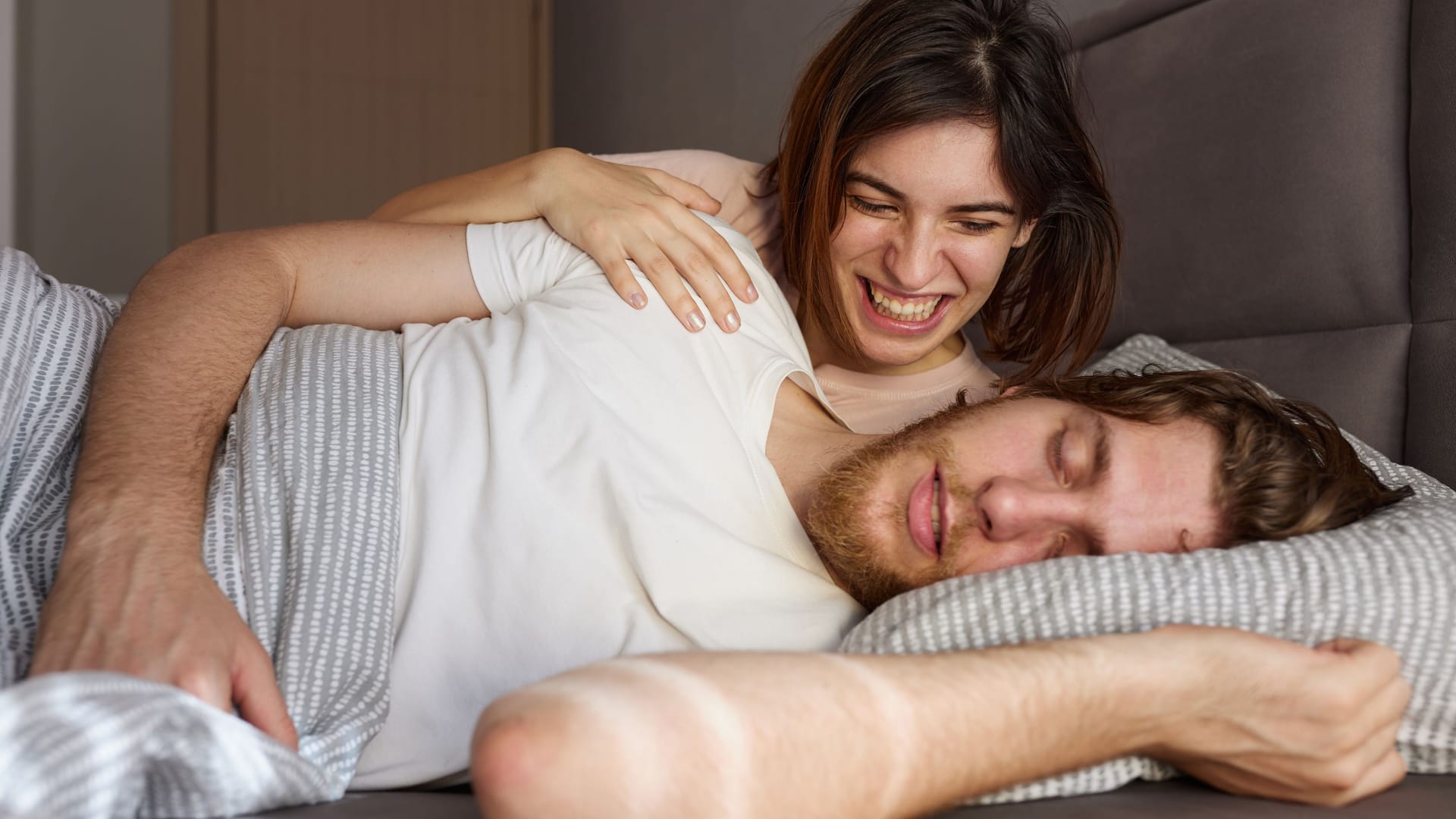 Frau liegt mit Mann im Bett und lacht Frau liegt mit Mann im Bett und lacht