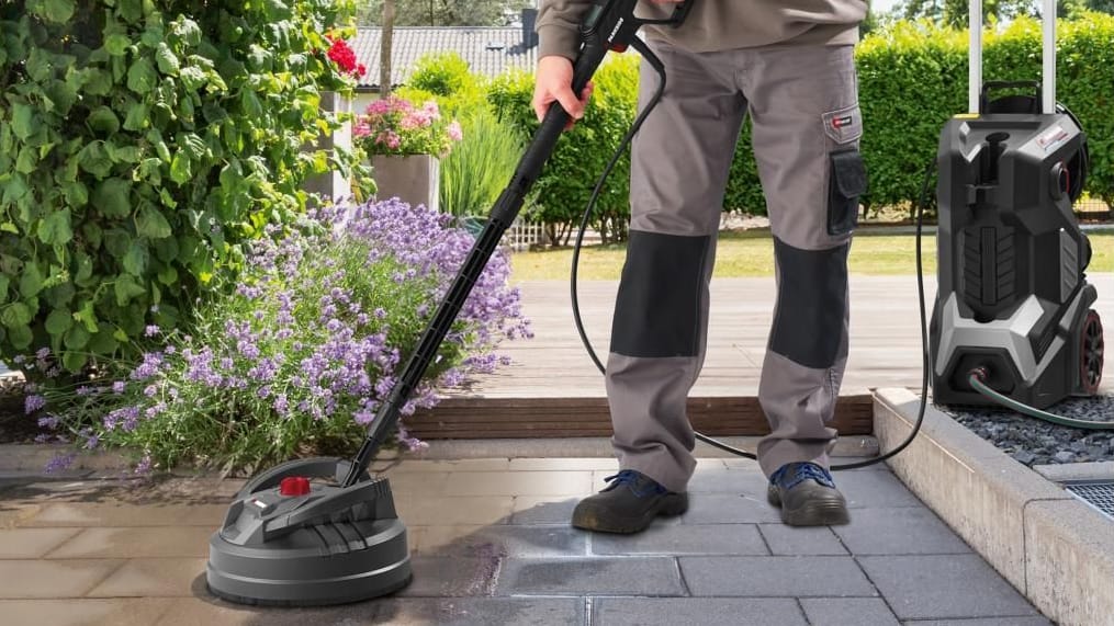 Mann nutzt Hochdruckreiniger auf Terassenfliesen Mann nutzt Hochdruckreiniger auf Terassenfliesen