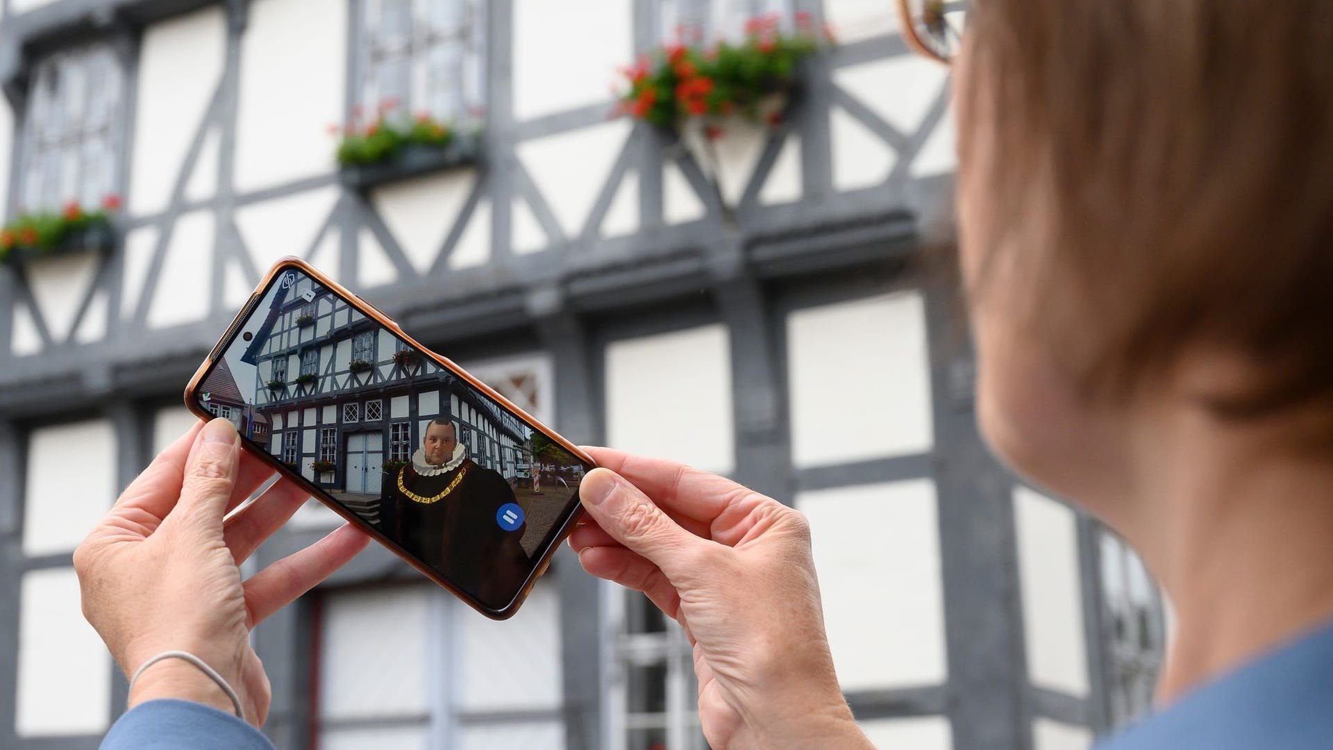 Claudia Filpe, Mitarbeiter der Touristik-Information Uslar, zeigt Erich II vor dem Rathaus auf einer Smartphone-App.