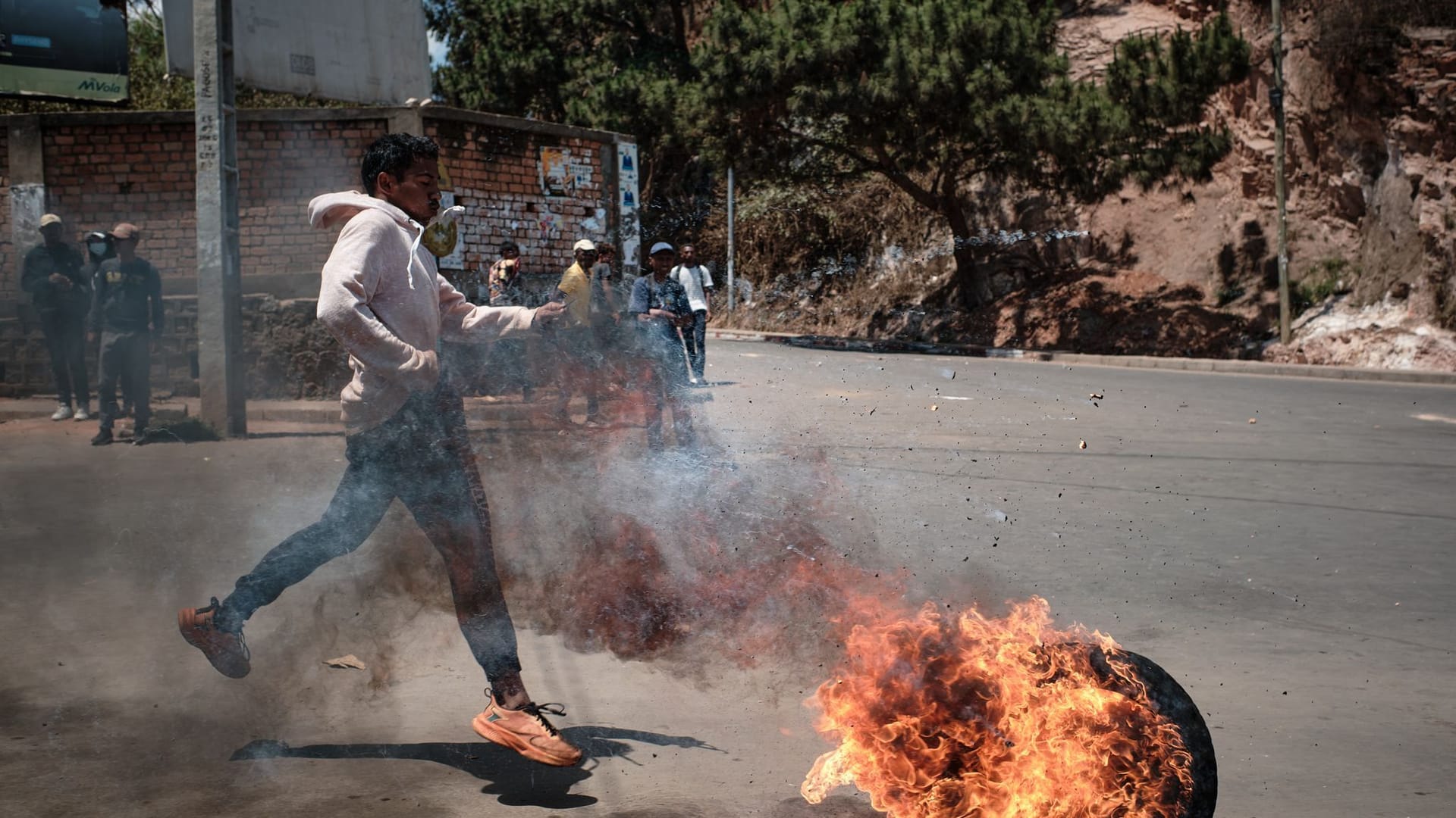 Antananarivo: Einer der Demonstranten schiebt einen brennenden Reifen in Richtung der Barrikaden, die von den Sicherheitskräften während des dritten Streiktages errichtet wurden. Antananarivo: Einer der Demonstranten schiebt einen brennenden Reifen in Richtung der Barrikaden, die von den Sicherheitskräften während des dritten Streiktages errichtet wurden.