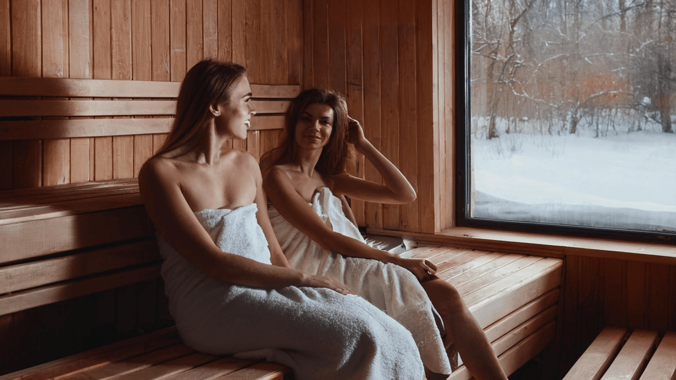 Zwei Frauen sitzen in der schwimmenden Sauna in Stade, während draußen der Schnee liegt.