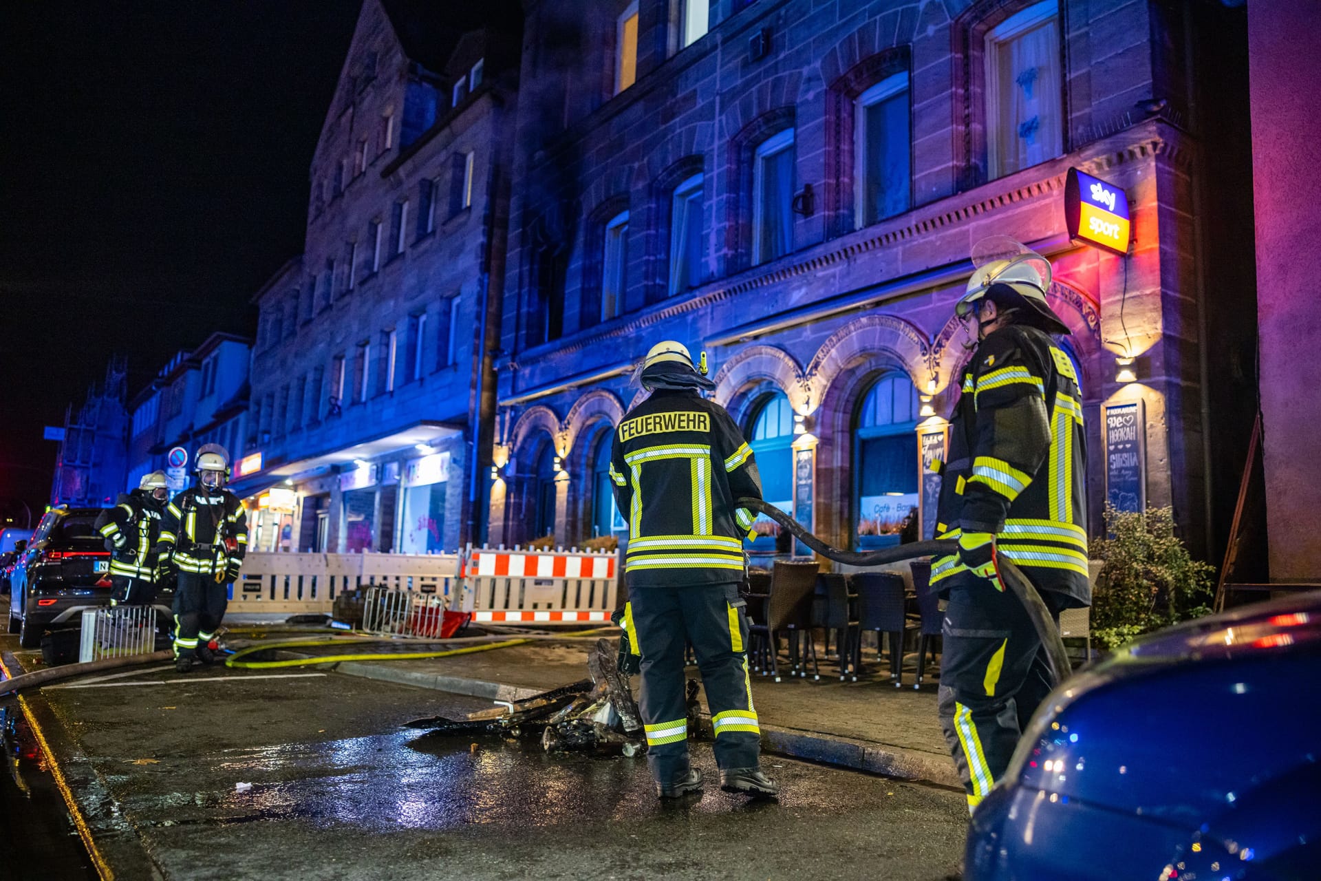 Feuerwehrleute stehen nach einem Brand vor einem Gebäude: Das Feuer war gegen Abend in einem Mehrfamilienhaus an der Königstraße ausgebrochen.