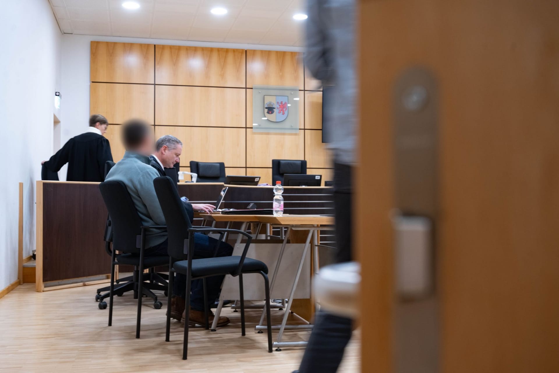 Der Angeklagte (l) sitzt neben seinem Verteidiger Frank Ackermann vor Beginn des Strafverfahrens im Verhandlungssaal des Landgerichts.